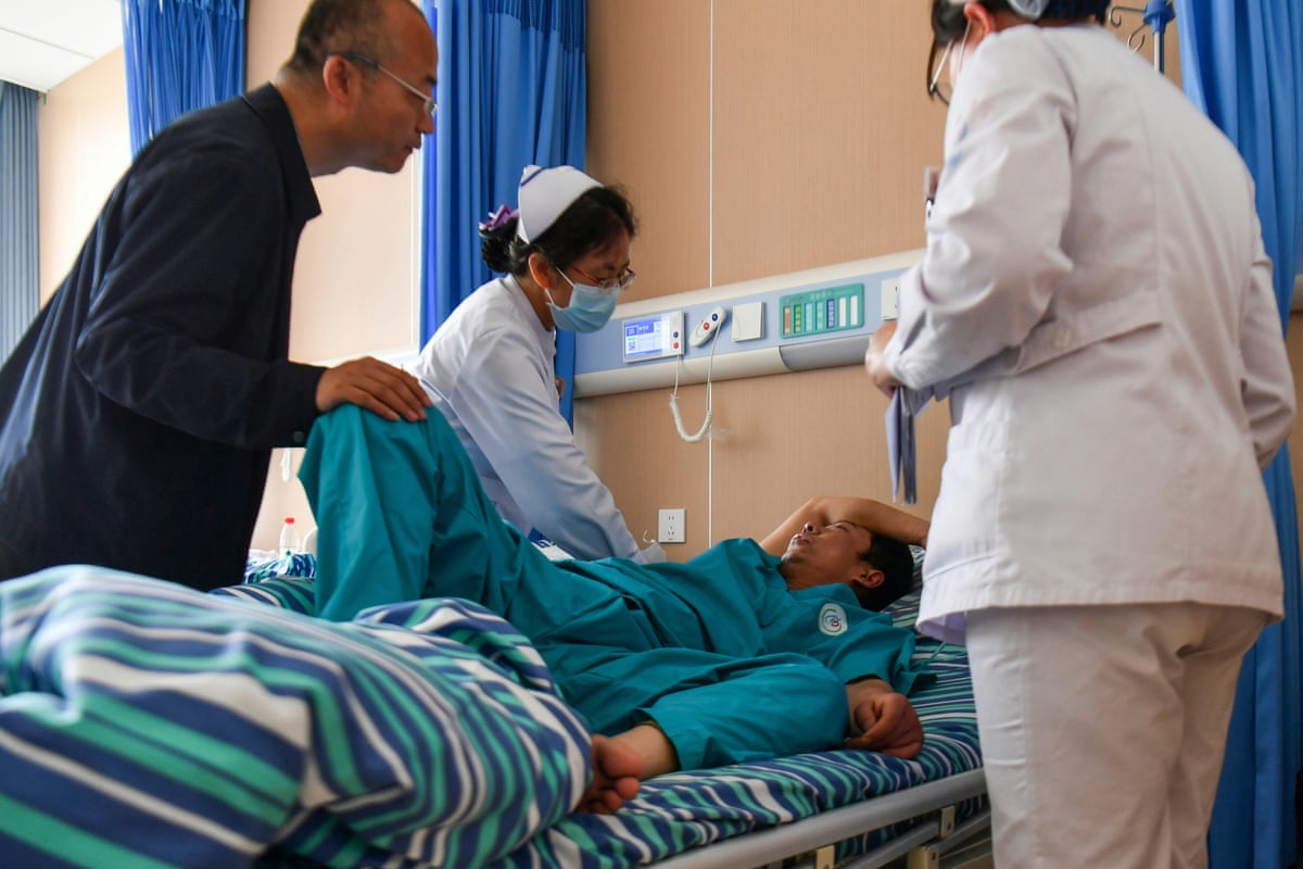 Medical staff attend to an injured mine worker in a hospital bed