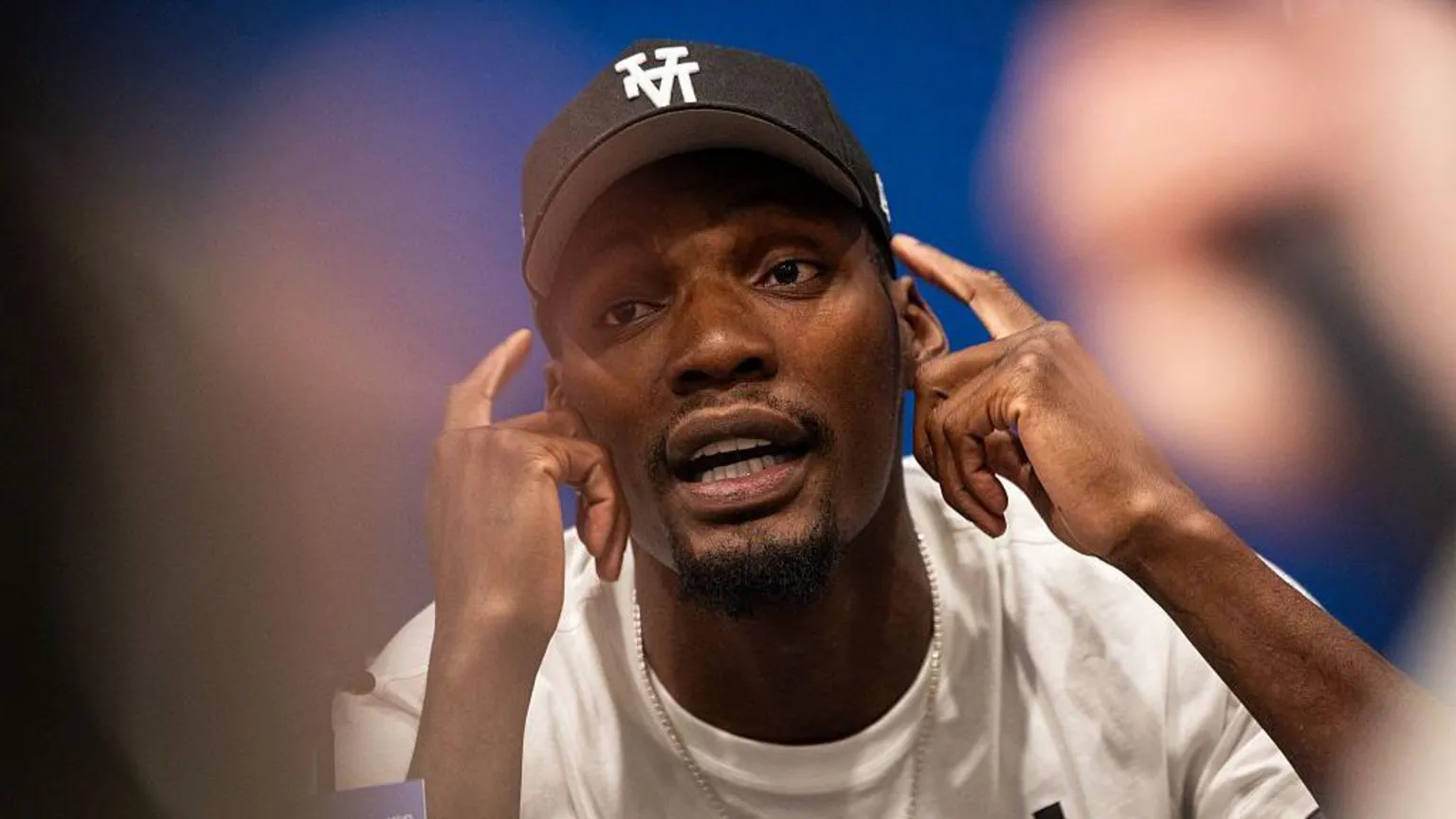AFP/ US track and field sprinter, Fred Kerley, talks with the press ahead of the Enhanced Games. He points to his face with his hands, mid-conversation.