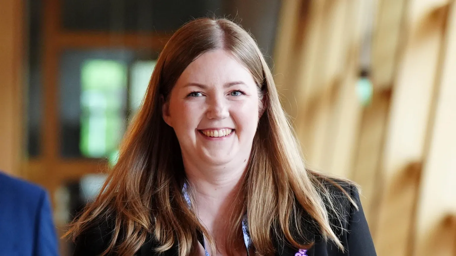  Gillian Mackay has long brown hair and wears a black blazer and lanyard