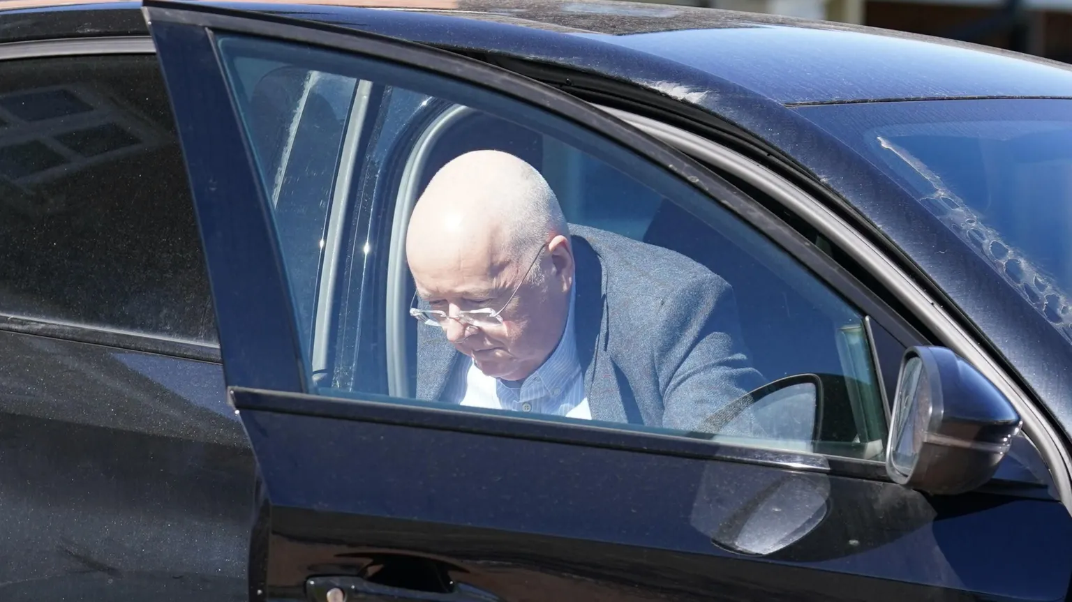 Peter Murrell gets out of a black car in April 2023. He is wearing a grey jacket and white shirt.