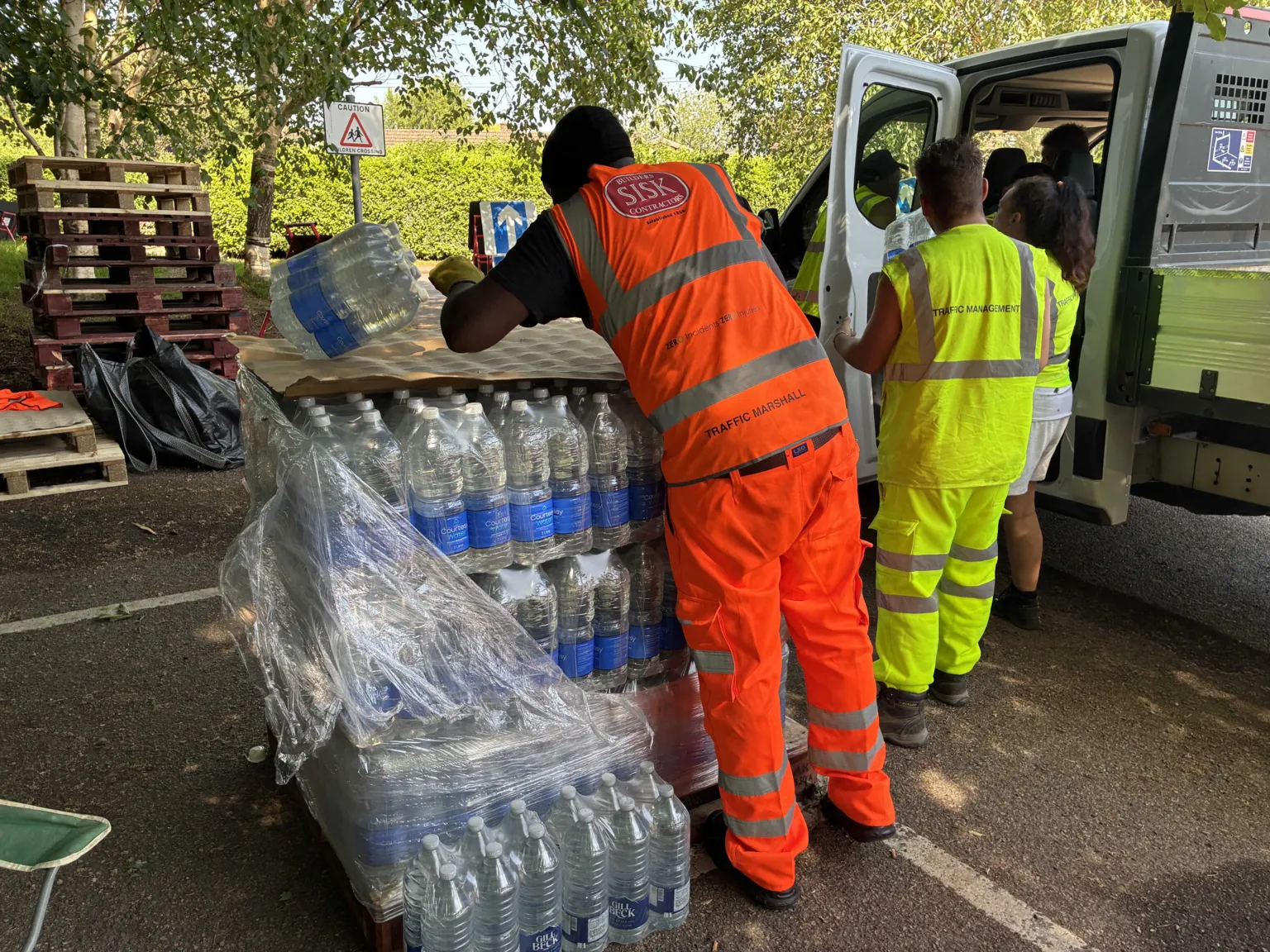 Simon Jones South East Water workers in orange and yellow high-visibility uniforms hand out bottled water in Ashford, Kent after 500 homes were left without water in Sussex and Kent.