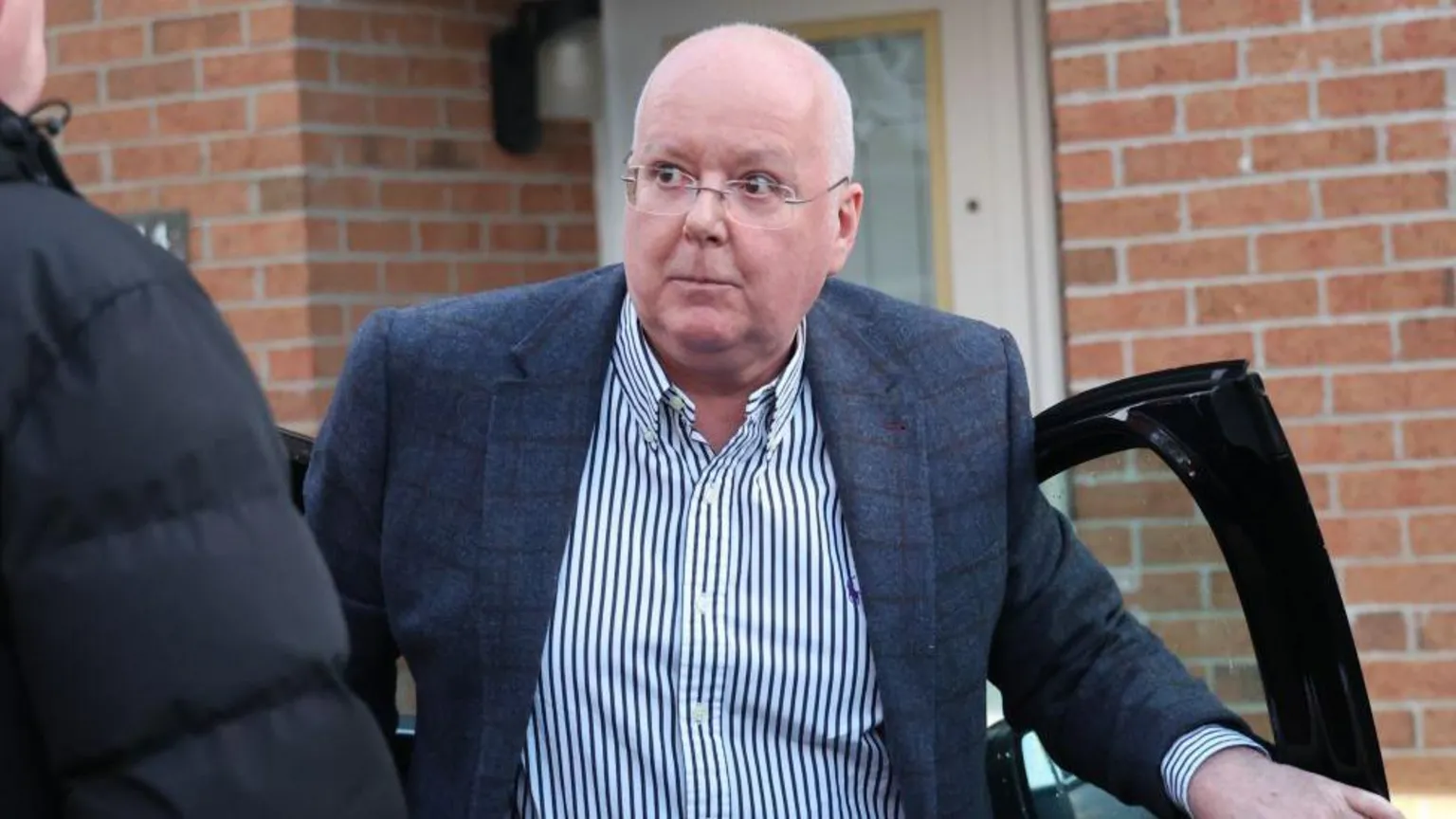 Peter Murrell climbing out of a car outside a modern home