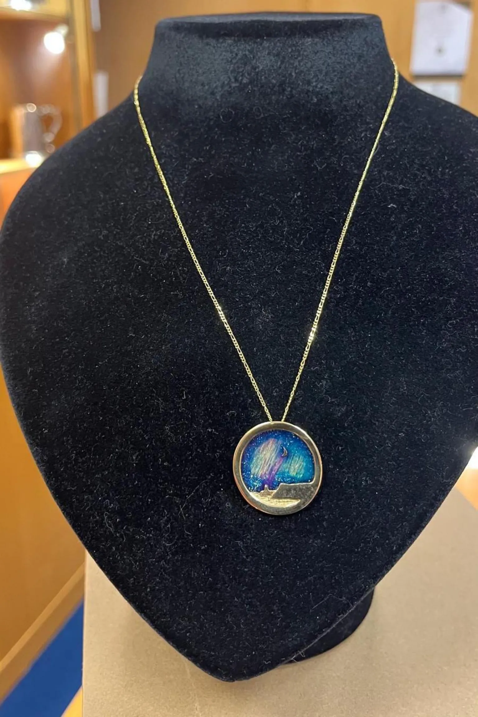 A silver pendant hanging on a display