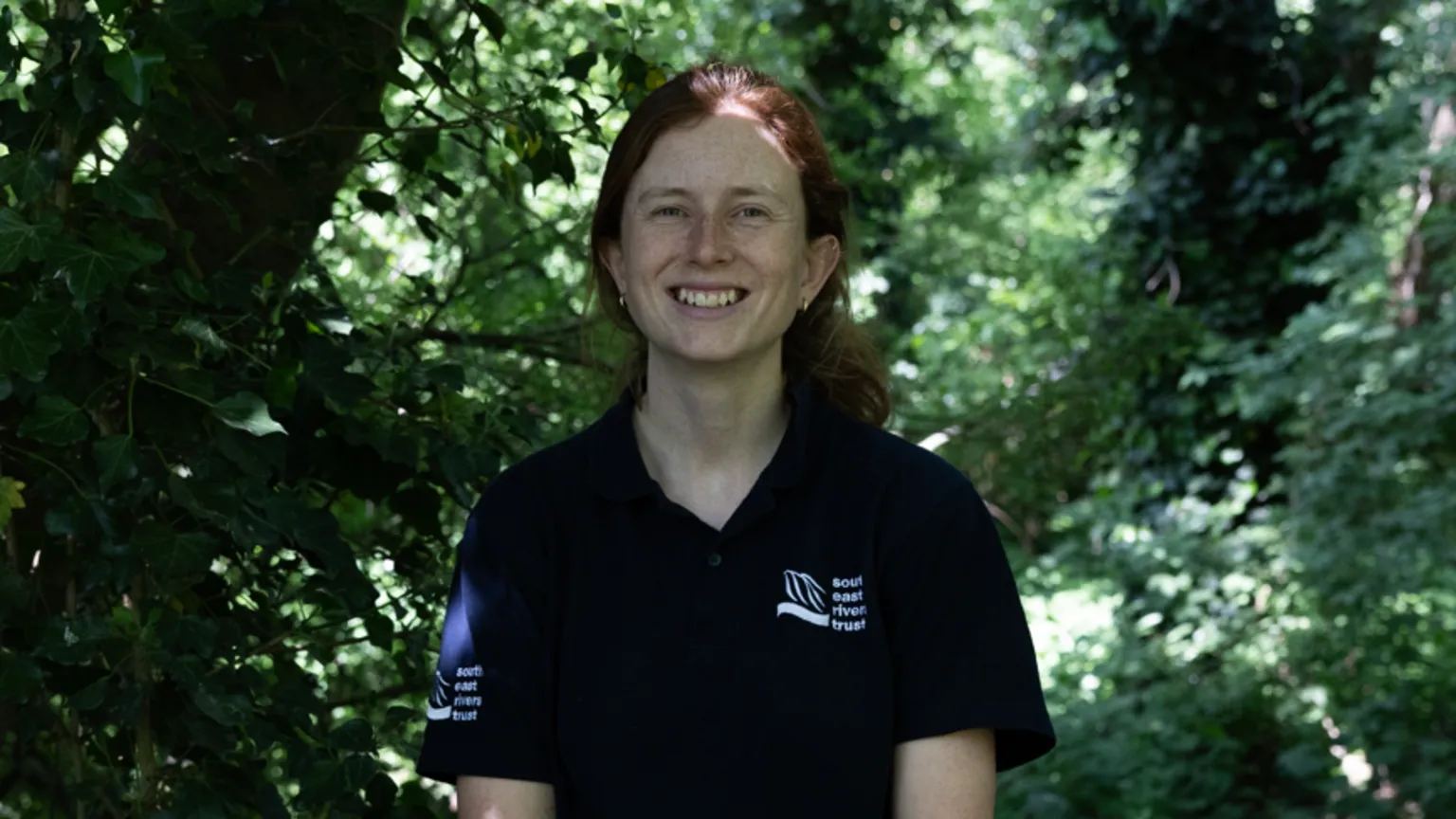 Facundo Arrizabalaga A woman with ginger hair smiles at the camera with green foliage behind her.