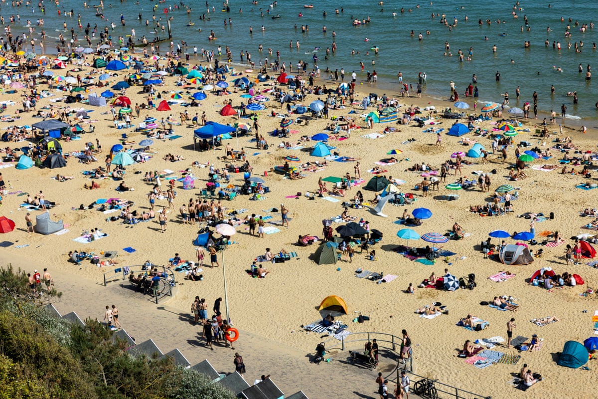 A photo taken from a raised perspective of a large amount of people spread across the beach