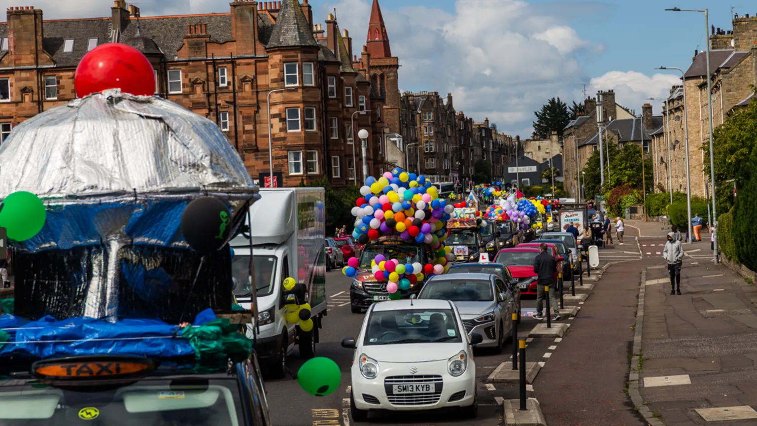 Mark Forsyth A parade of brightly coloured taxis travels down a residential street