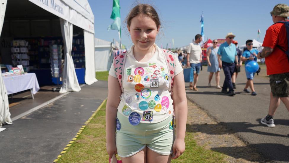 Ydych chi'n gallu cyfri sawl sticer sydd ar grys-ti Bethan o Fae Colwyn?
