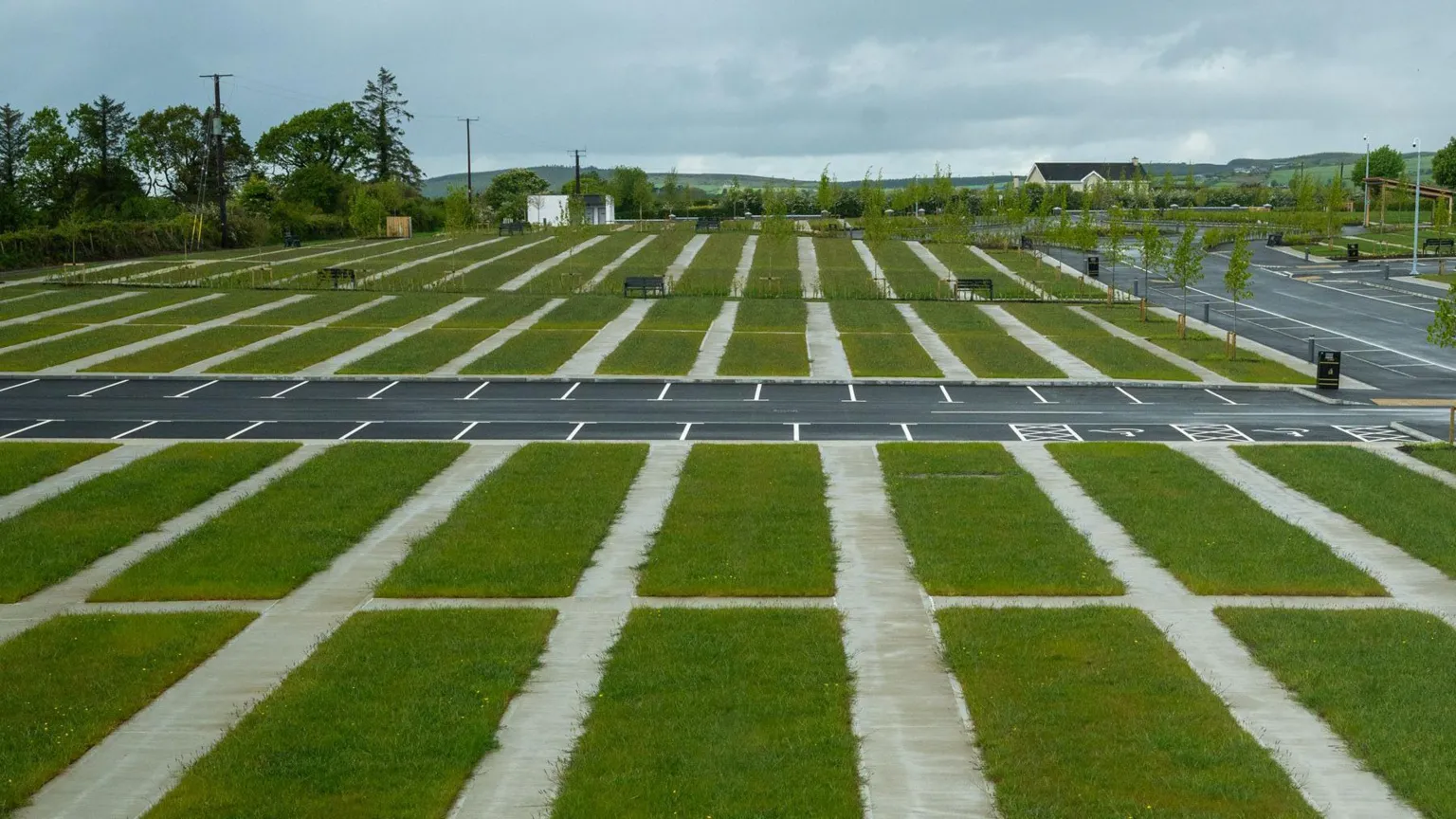 DCSDC A wide shot of the new cemetery. A row of grassy areas are visible with a number of parking spaces in the background.