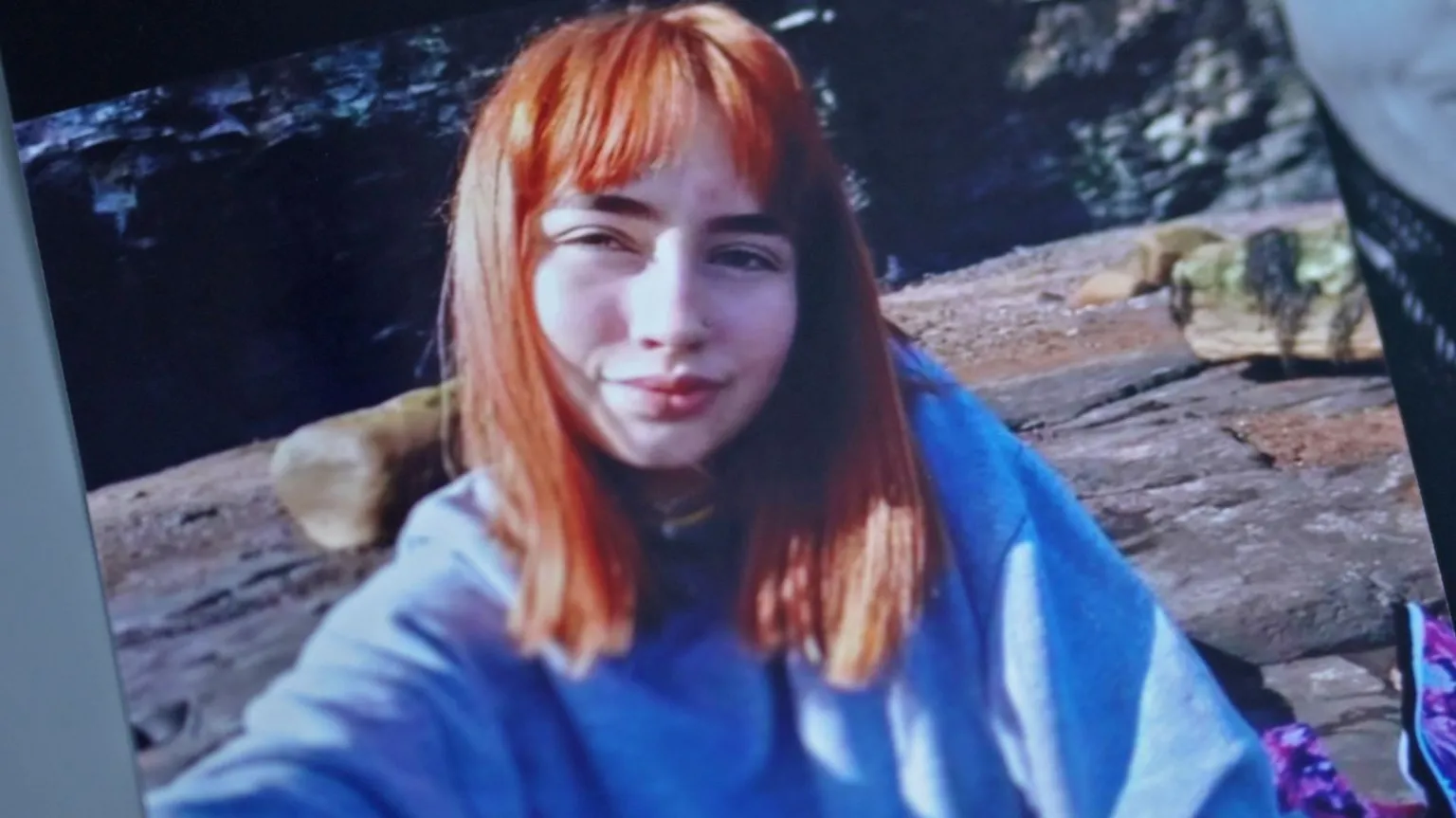 Family handout A teenage girl with straight red hair is looking at the camera. She is wearing a blue-grey top. The image is a photo of a photo, and so there are slanted lines either side of the image where the original photo ends.