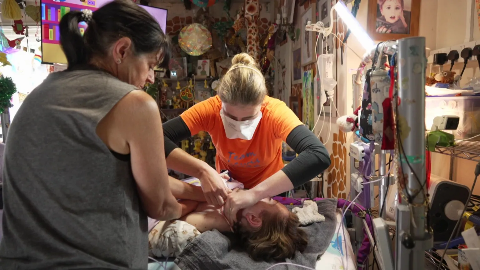 Jenny Dunning/BBC Samantha and one of Lewis' nurses cleaning his neck for his tracheostomy tape change. 