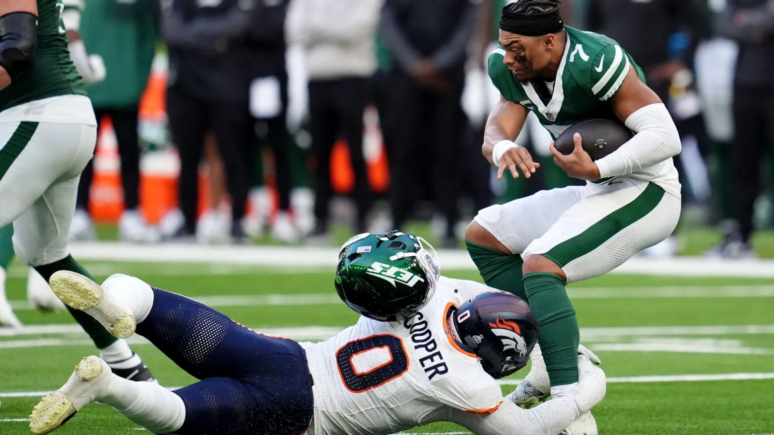  An American footballer wearing green is tackled by one wearing white