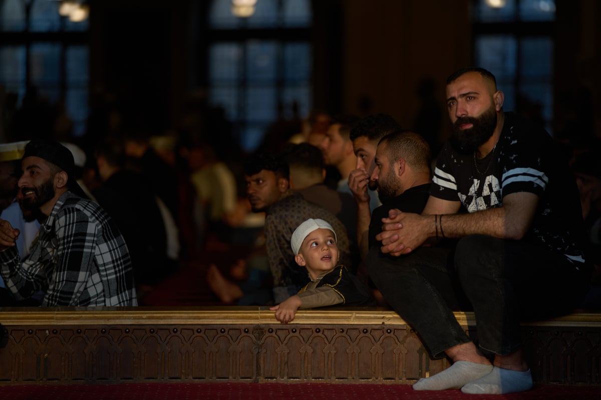 A child looks at a man inside a mosque filled with worshippers.