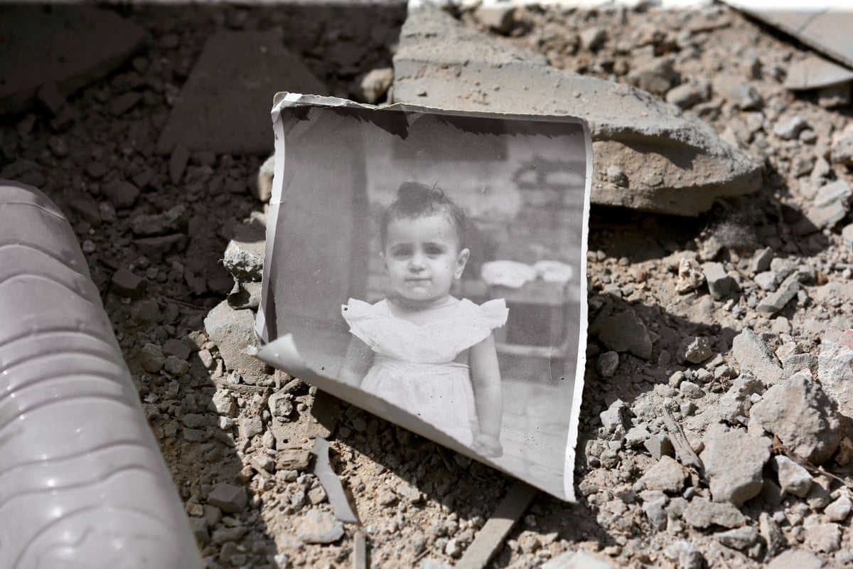 A photograph of a child lies on the ground of a destroyed home.