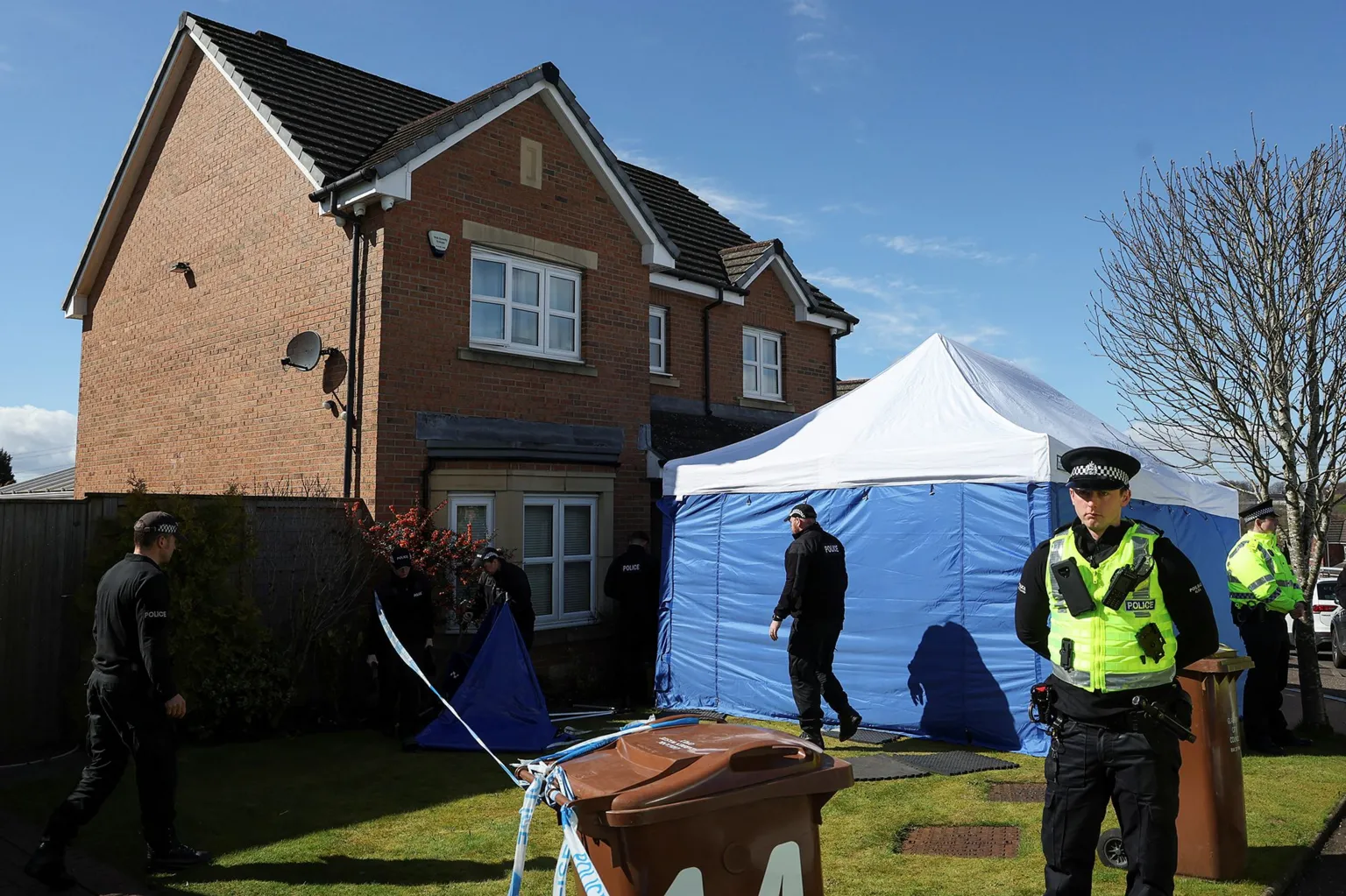 A blue police tent outside a modern house