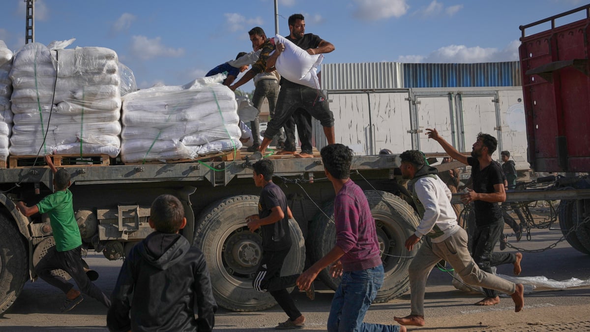 People grab sacks of flour from a moving lorry carrying World Food Programme aid in Gaza.