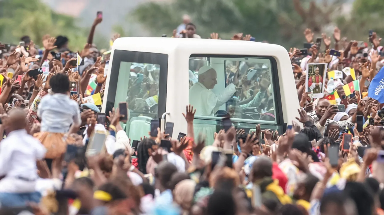 AFP via Crowds surrounding Pope Leo's white vehicle after he landed in Yaoundé, Cameroon