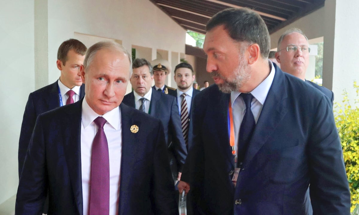 Deripaska speaks to Putin as they walk towards the camera, followed by other men in suits