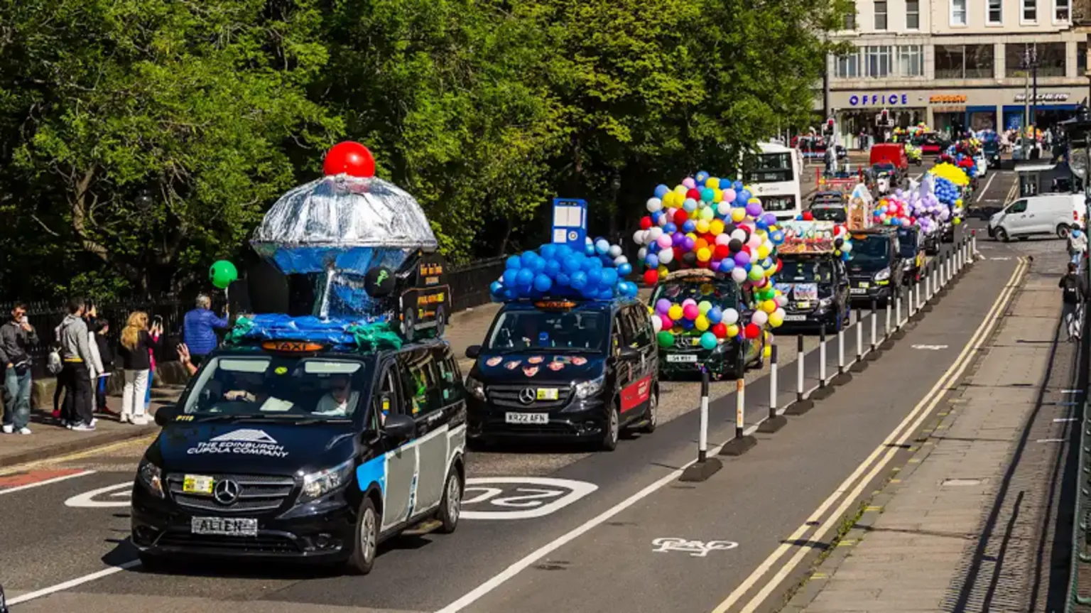 Mark Forsyth A queue of black cabs decorated with bright balloons driving up the Mound in Edinburgh