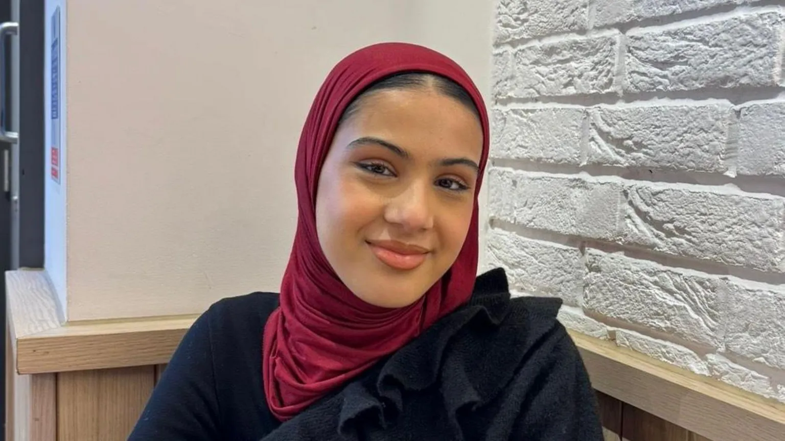 Spear Zaynah wearing a burgandy headscarf and black top 