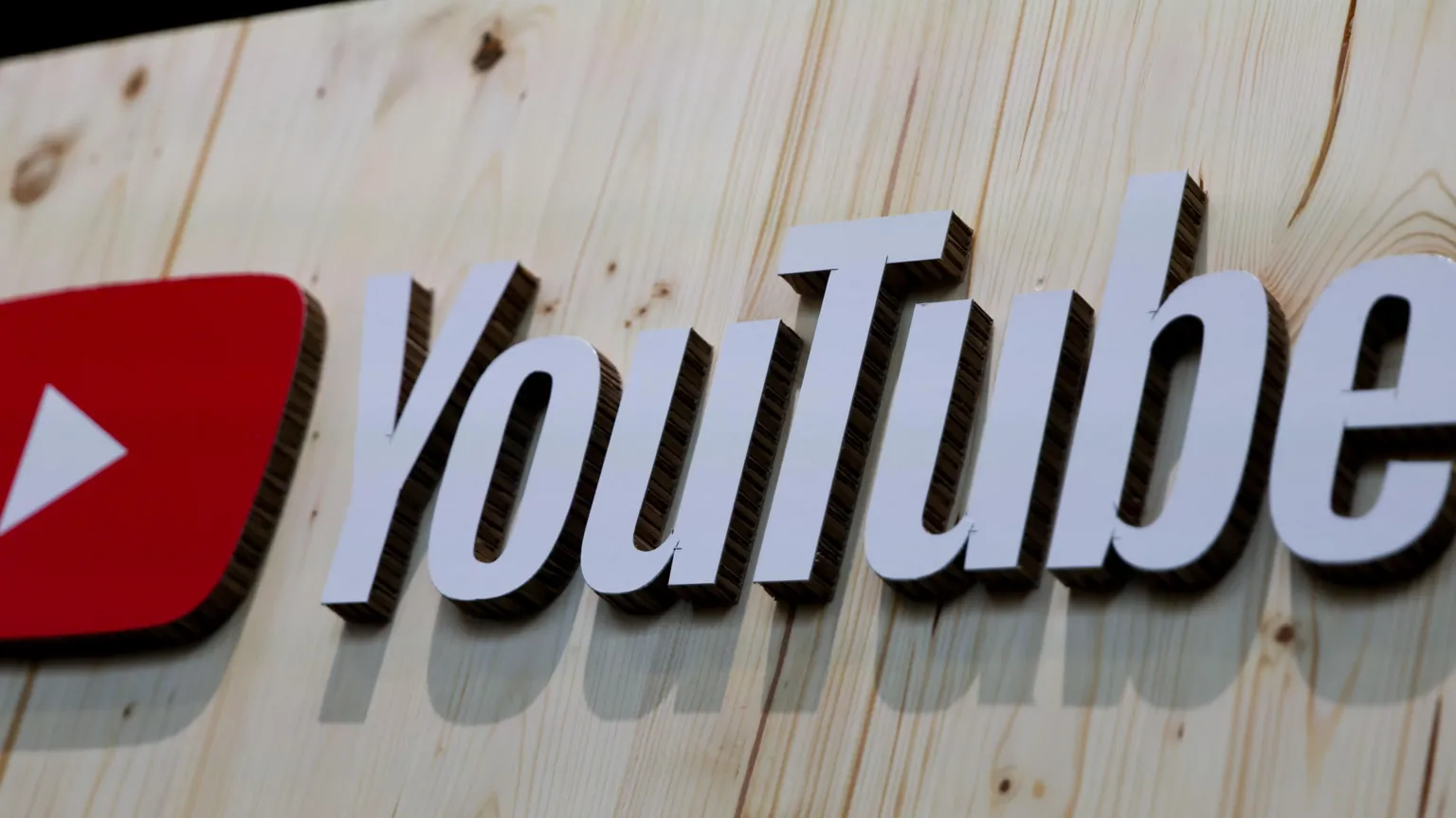 EPA The YouTube logo, in white writing beside the play button symbol of a white triangle on a red background, placed on light wooden boards.