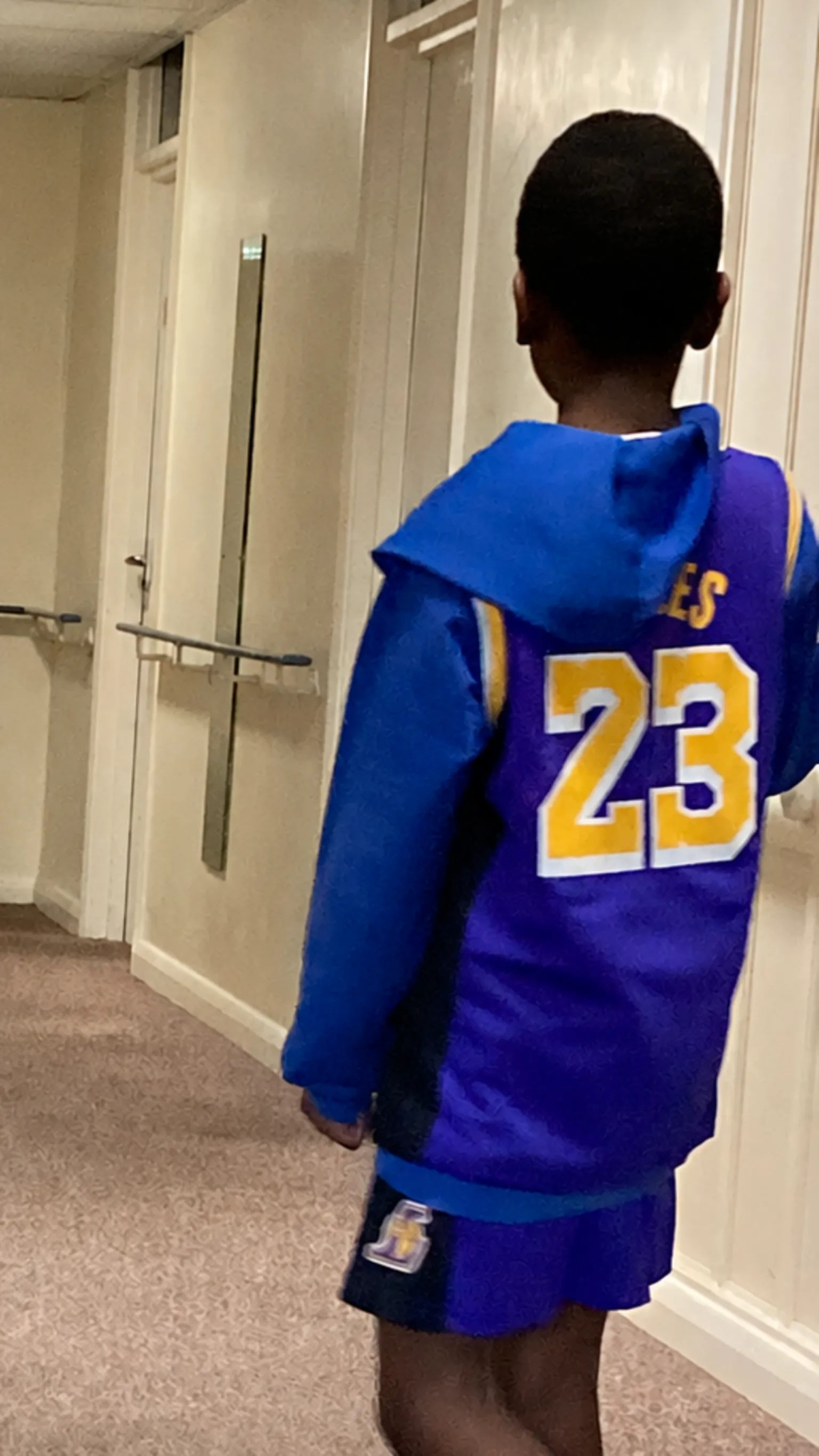 Shantel Morris A boy with his back to the camera. He is wearing a bright blue top with the number 23 on it