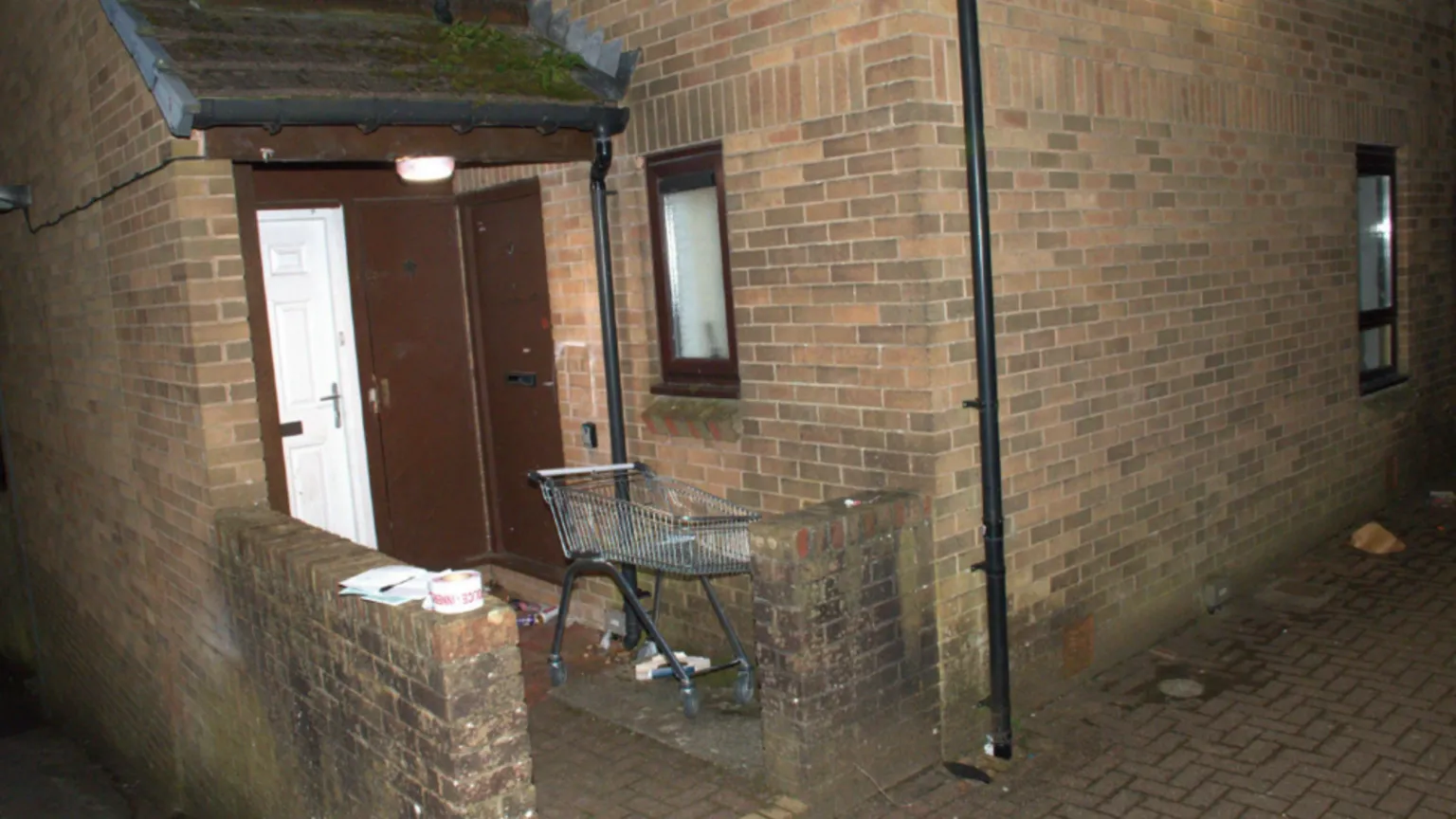 South Wales Police / CPS The outside of a brick house, with a brown door. There is rubbish on the ground outside and a shopping trolley. 