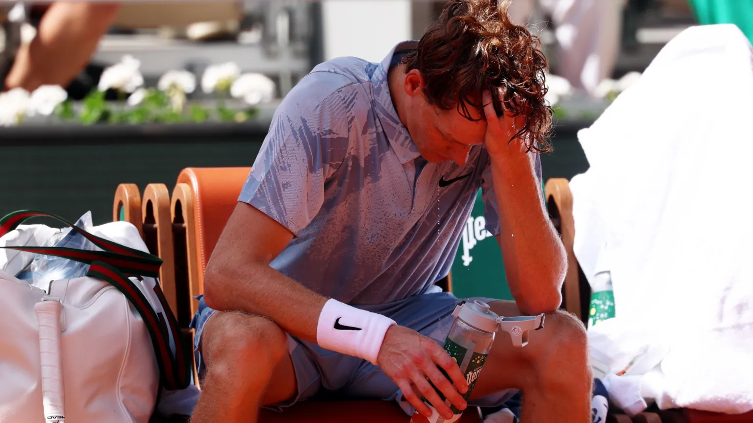 EPA Jannik Sinner holds his head in one hand as he drinks water in the heat during a break at the French Open.
