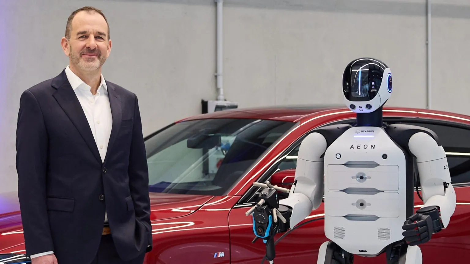 BMW Aeon robot stands alongside Michael Nikolaides, who is dressed in a dark suit and white shirt.