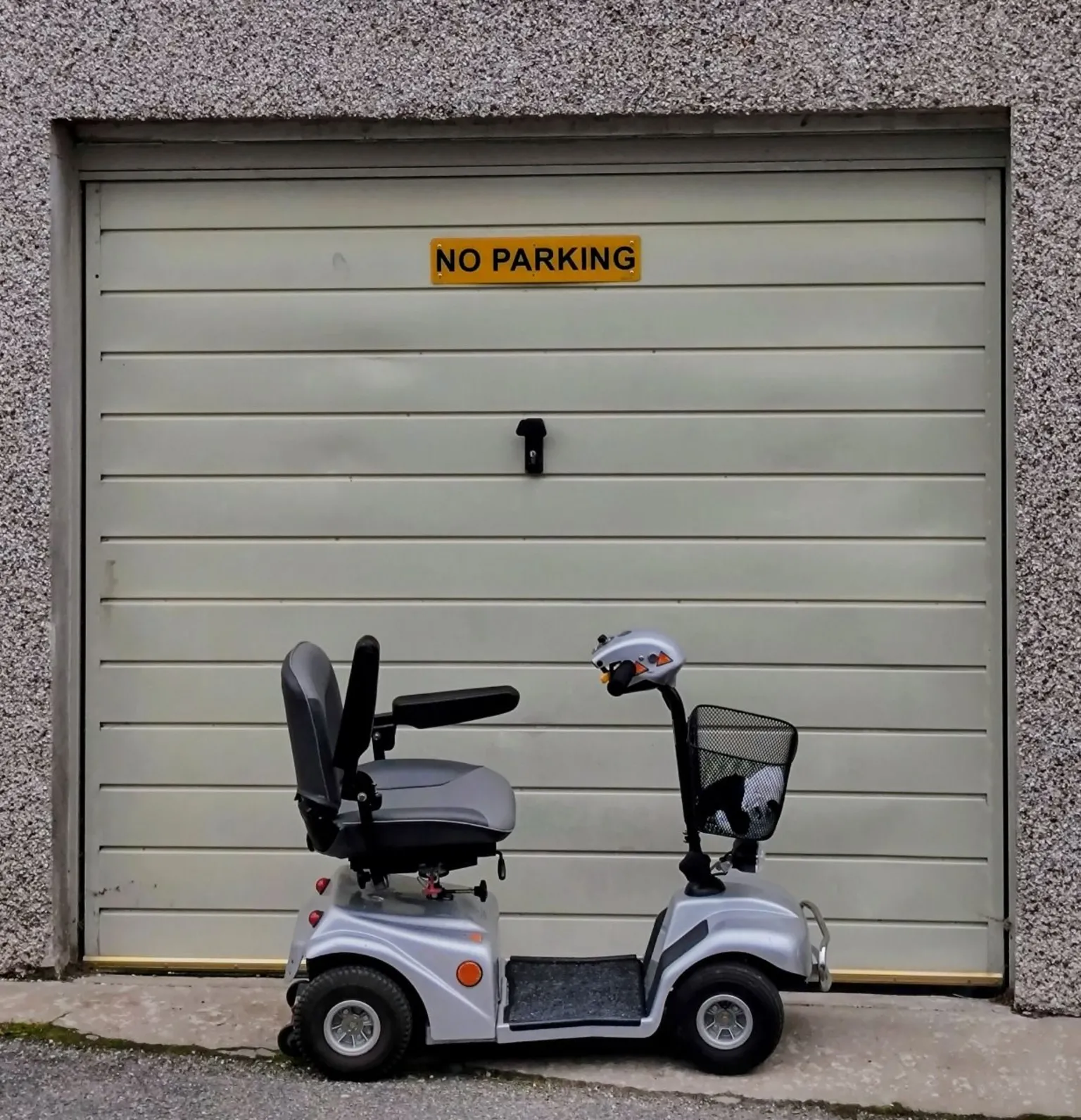 Stephen Choate A mobility scooter parked outside a garage door with a No Parking sign