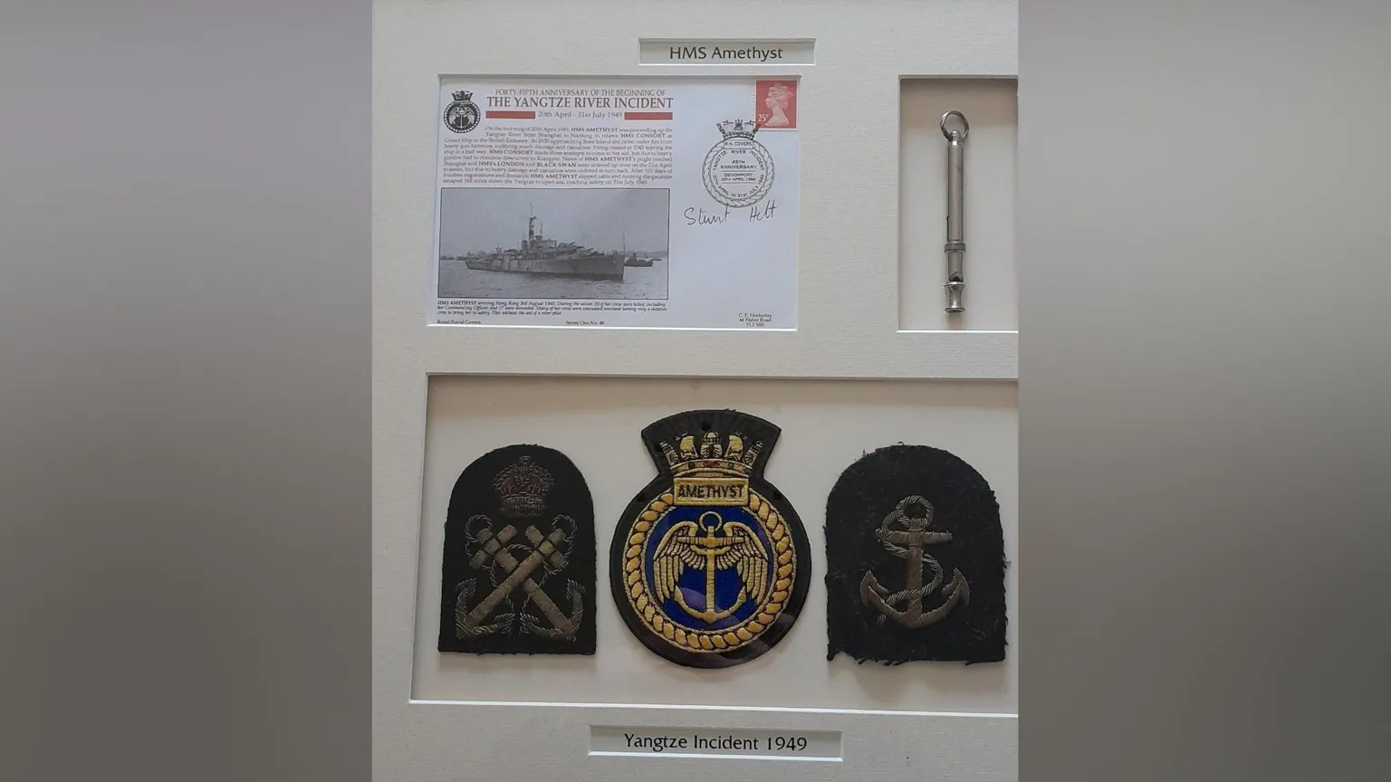 Raymond McCullough A white frame with badges and a piece of paper detailing the Yangtze incident.