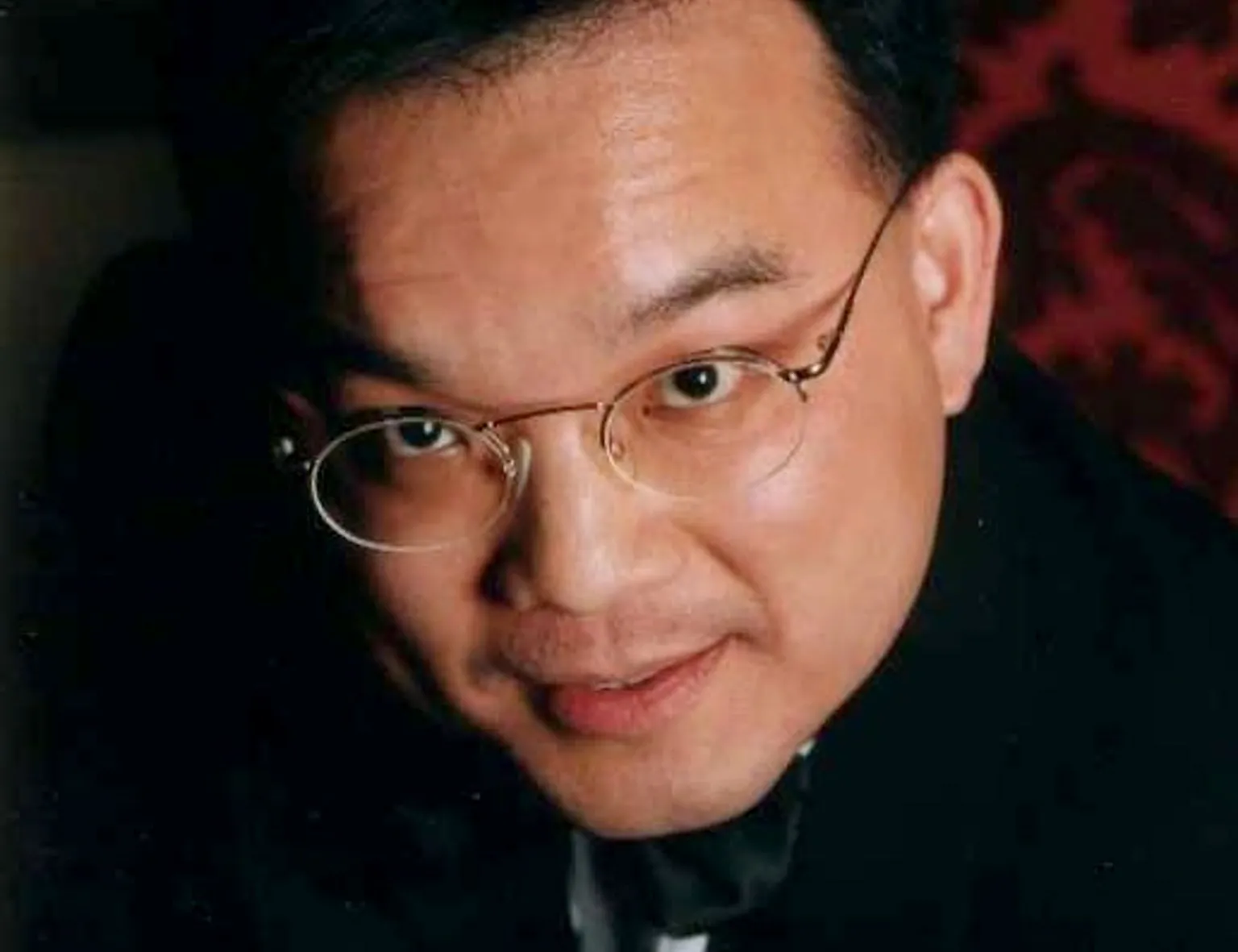 Close up image of Kenneth Law's face. He is looking at the camera and is wearing glasses.