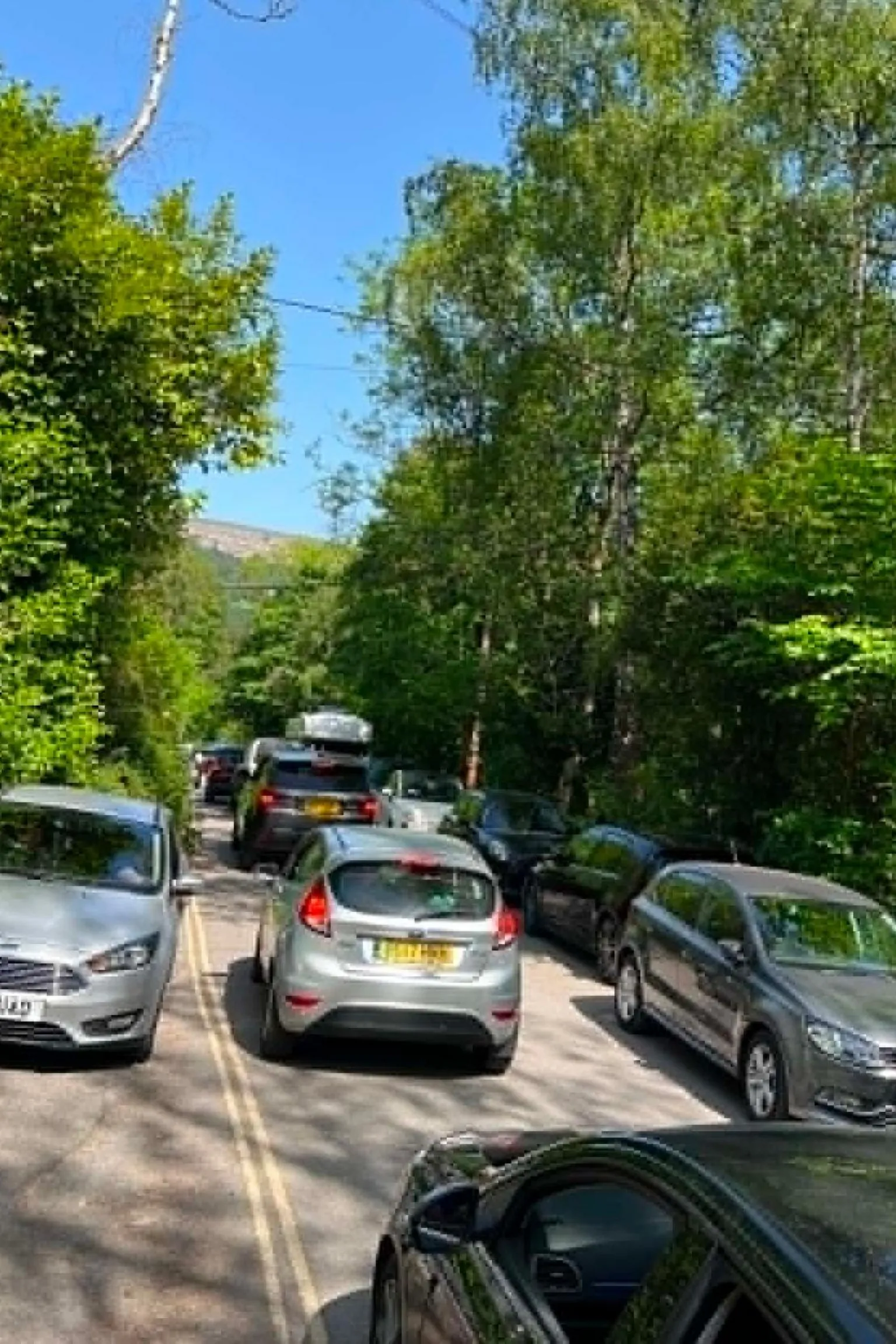 Tabitha Cars parked on either side of the road. There is stationary traffic in the middle of the road. 