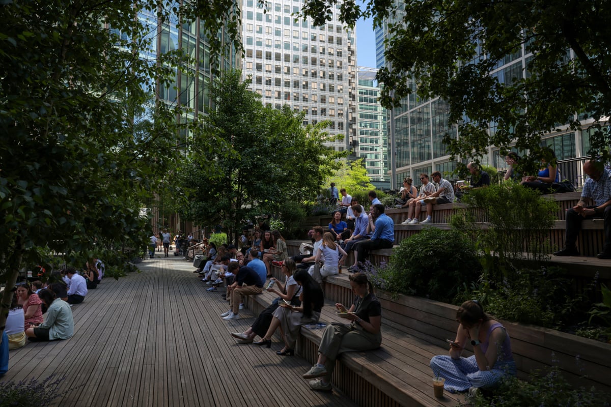 People sit on benches in the shade in Canary Wharf 