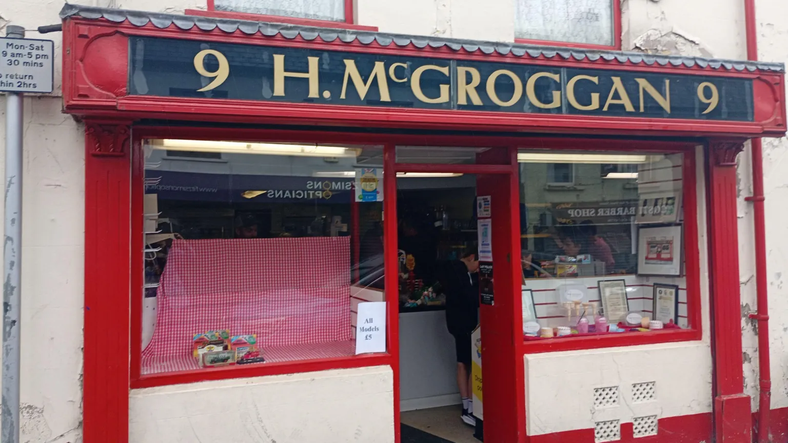 A shop front that is red. It has the name in gold letters, H.McGroggan 9.