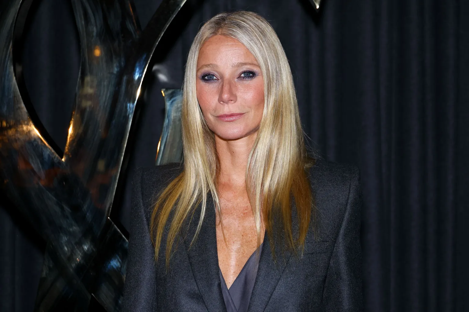  Gwyneth Paltrow looking at camera at a red carpet event. She wears a navy blazer dress and has long blonde hair. 