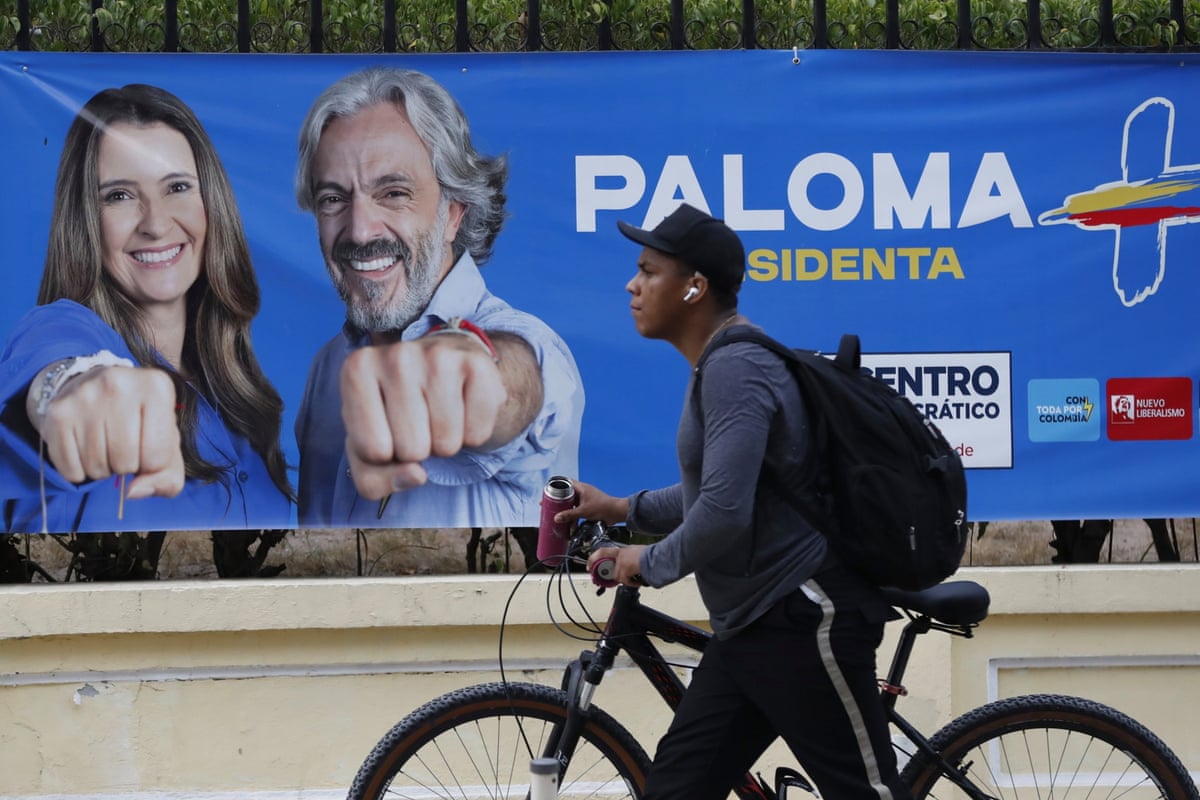 A person wheels a bike past a campaign poster for presidential candidate Paloma Valencia in Barranquilla, Colombia.