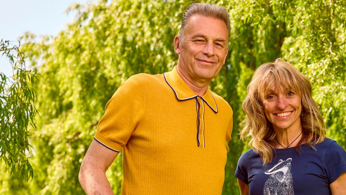 A man with short hair wearing a yellow shirt and a woman with blond hair wearing a black T-shirt with trees in the background