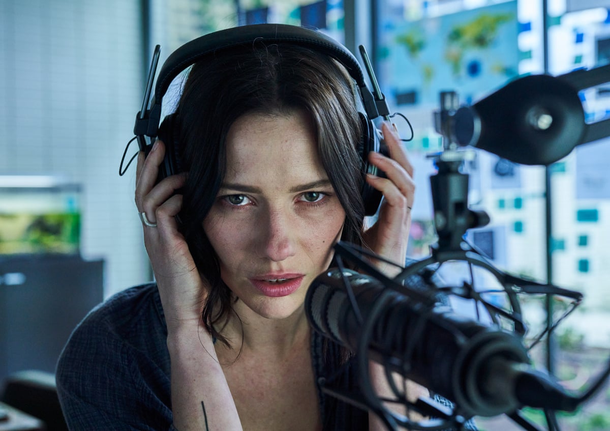 A woman sat in front of a microphone wearing headphones
