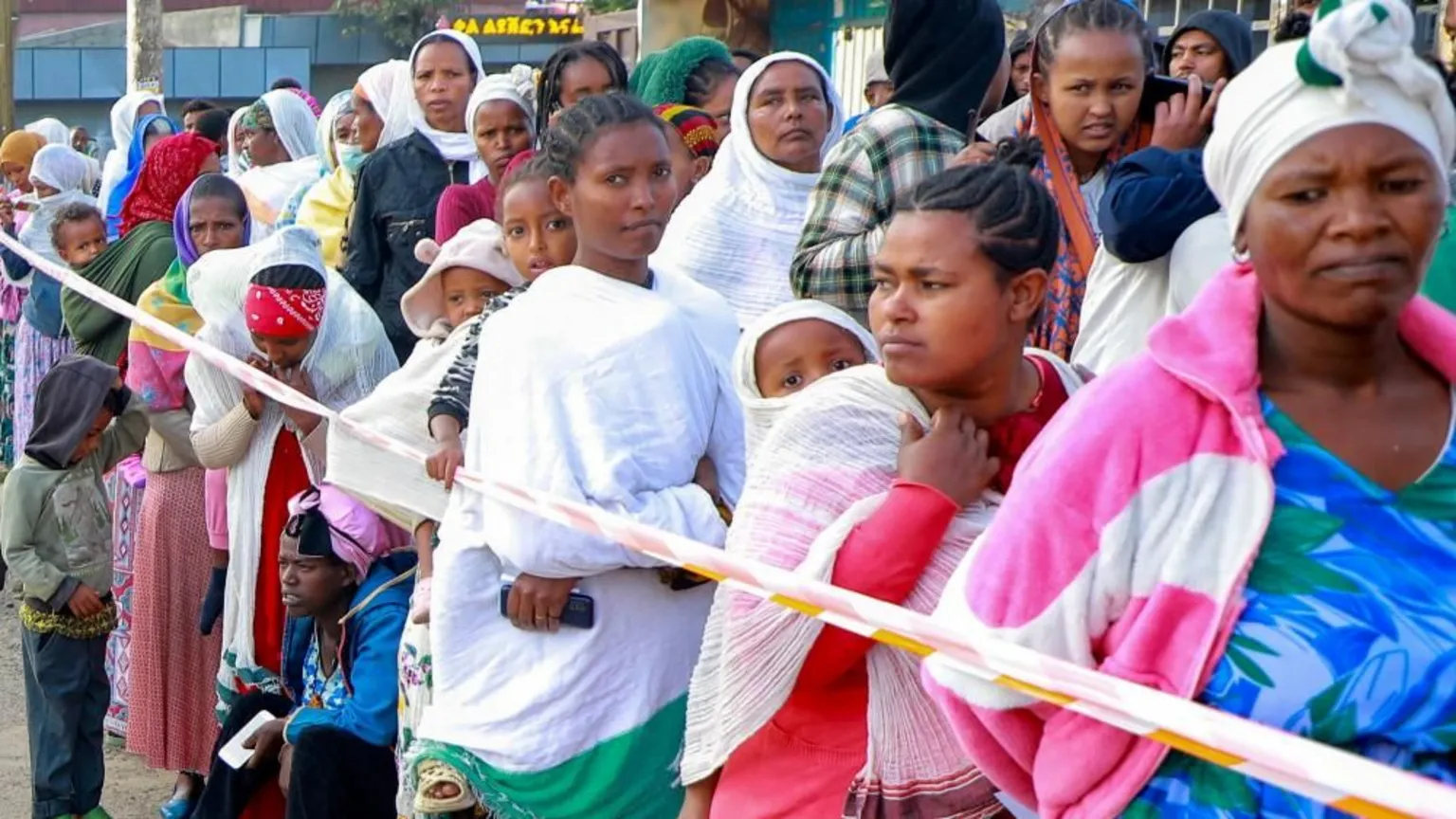A queue of women voters stand alongside some plastic tape marking the queue.