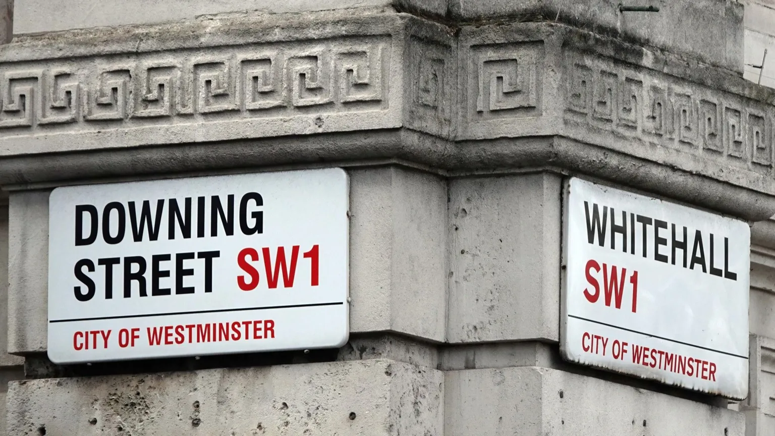 Signs for Downing Street and Whitehall on walls where the two streets meet.