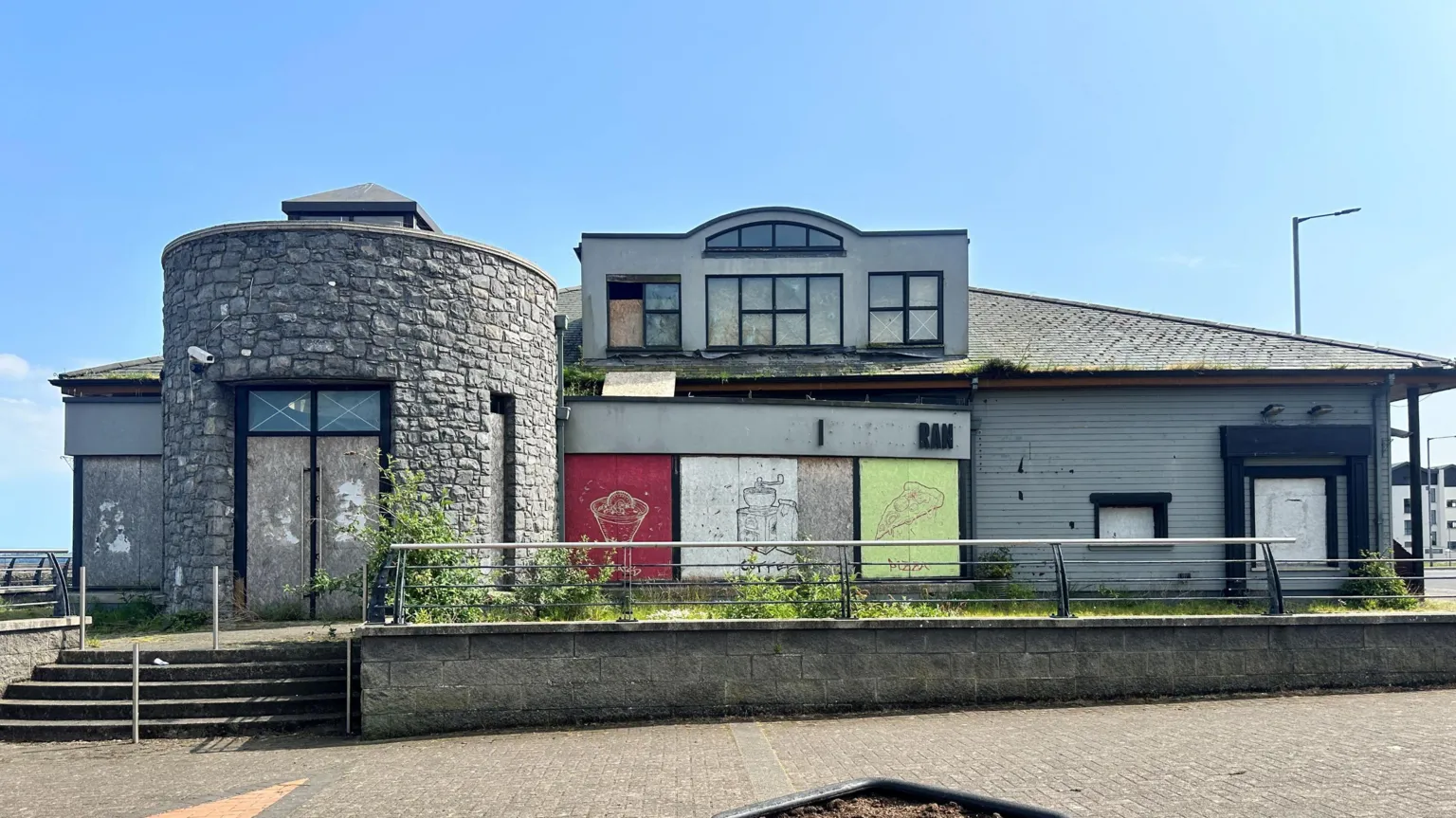 The derelict building that was formerly The Swift bar and restaurant. It is a large grey building with boarded up windows.