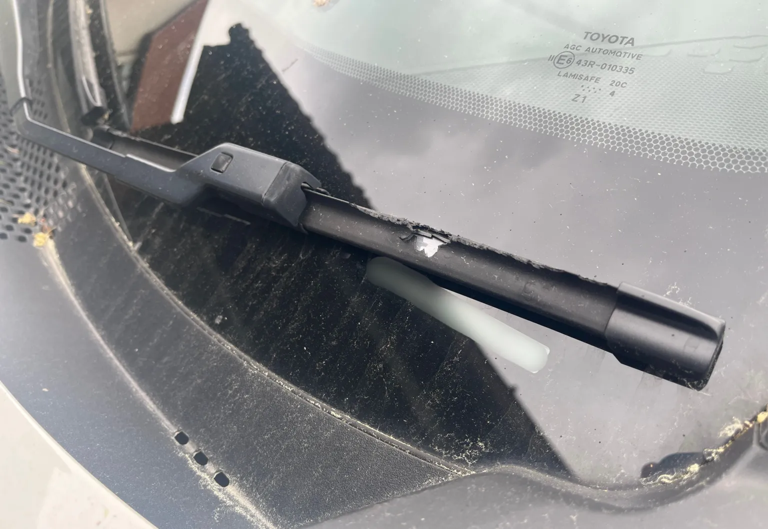 A photograph of a windscreen wiper with a large chunk out of the rubber