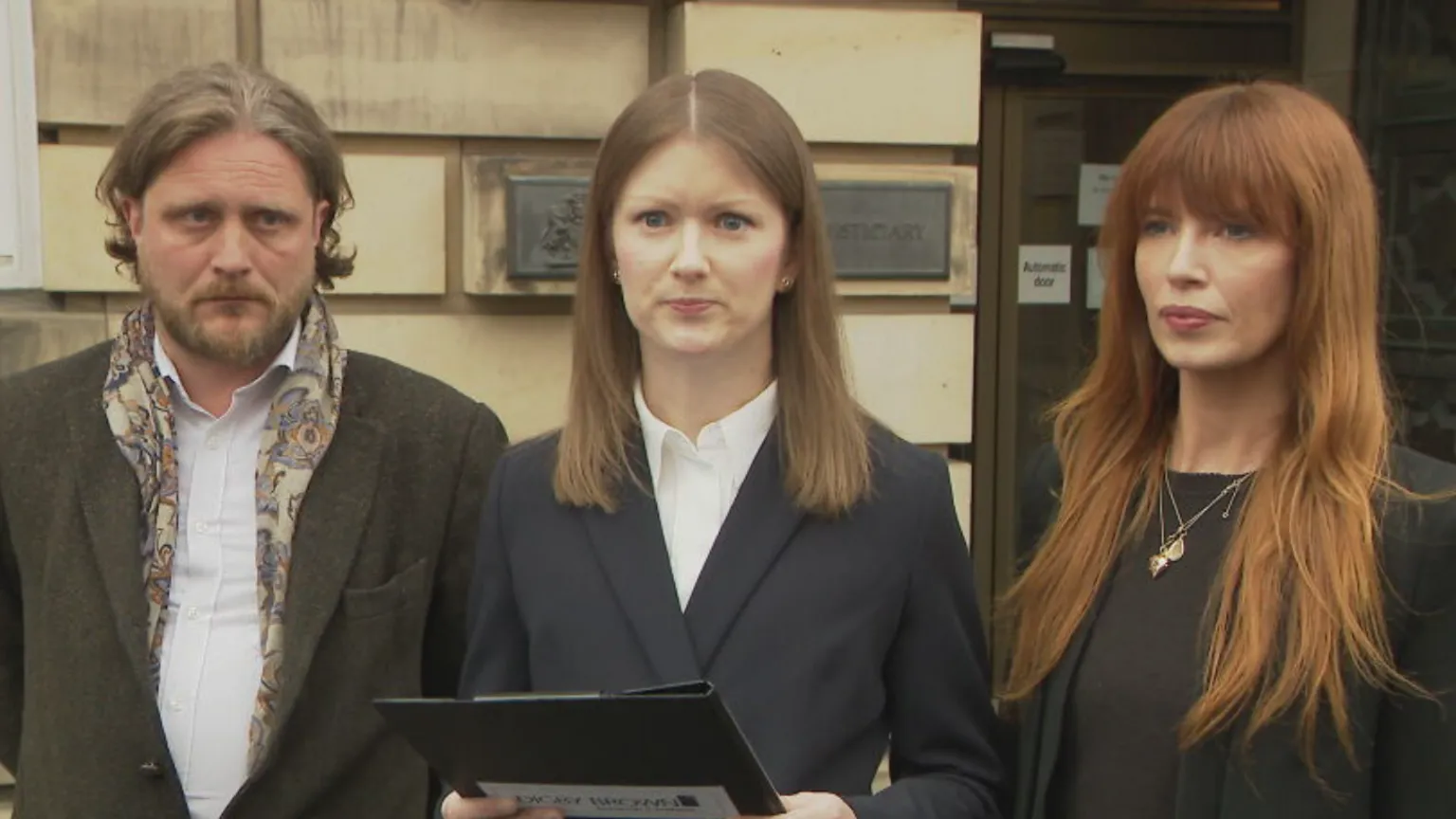 Three people wearing suits outside the High Court in Edinburgh