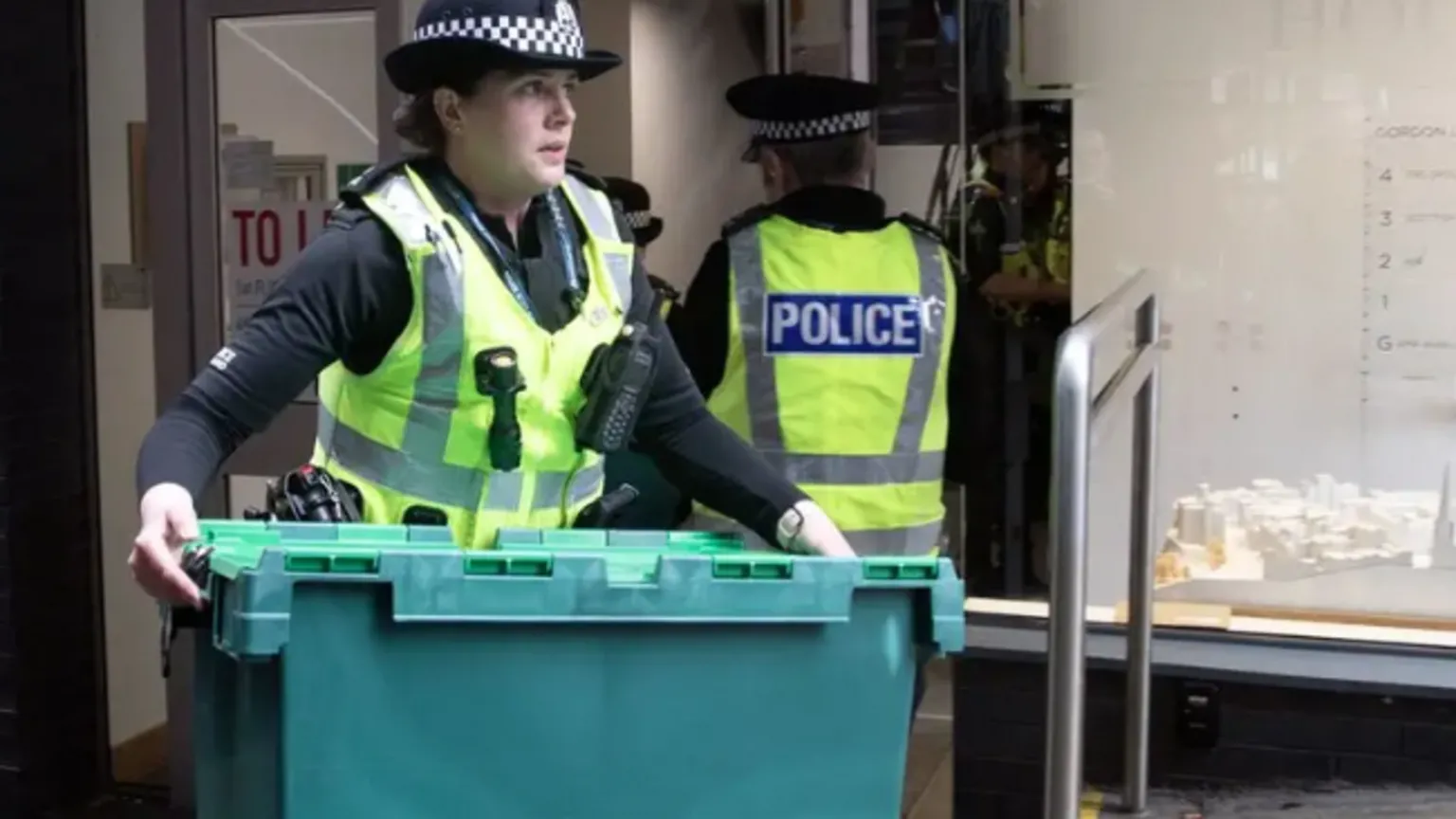 Police woman holds box outside an office