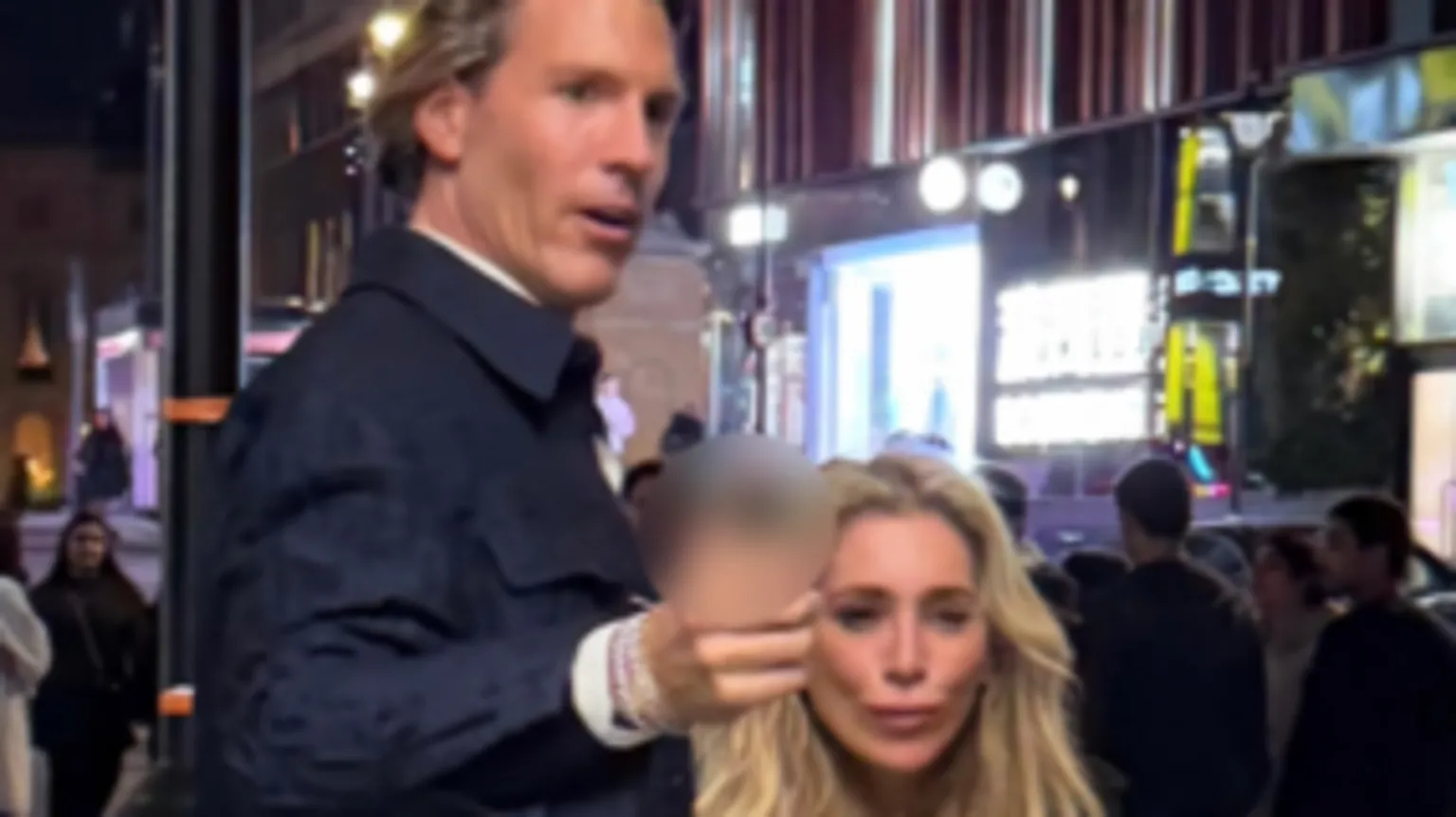 British Transport Police A CCTV image showing a tall man with brown hair wearing a smart dark blue jacket, gesturing forward. He is with a woman with long, blonde hair
