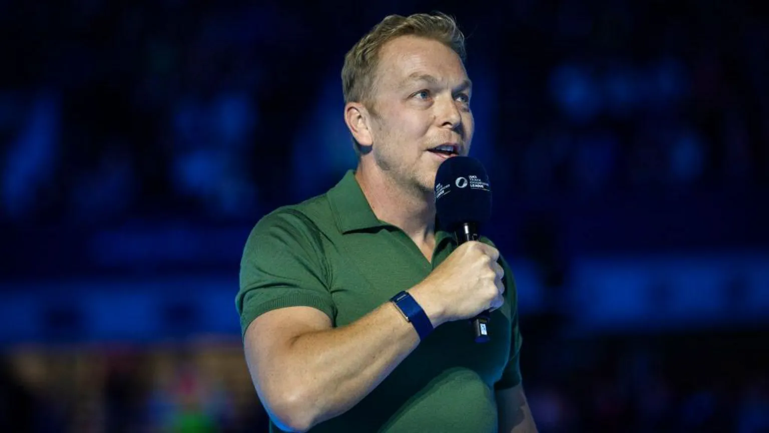Former track cyclist and Olympian Sir Chris Hoy addresses a crowd at Lee Valley Velopark Velodrome on 7 December, 2024. He wears a short sleeved green polo shirt and holds a microphone