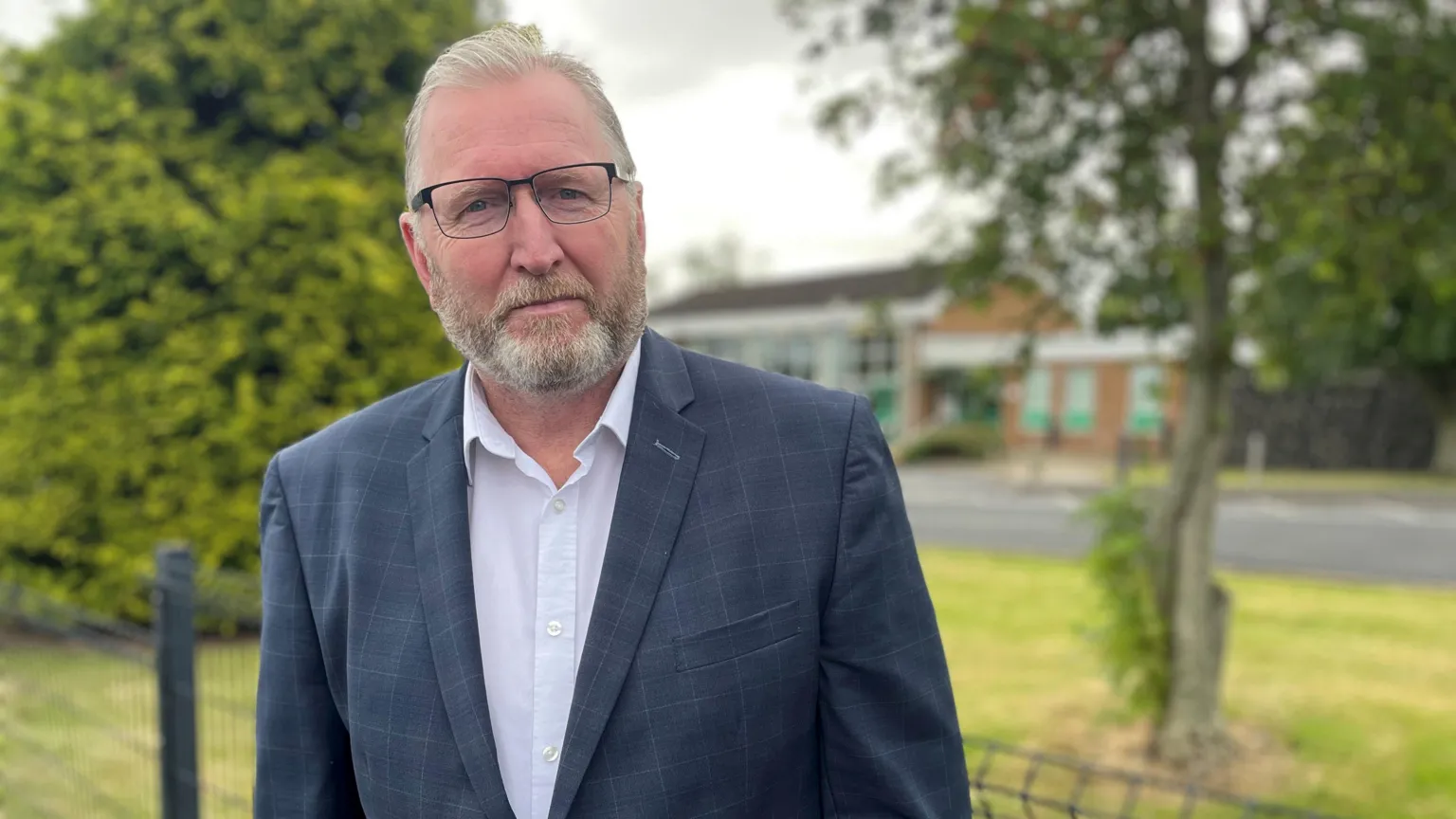 PA/Jonathan McCambridge Doug Beattie has grey hair and a grey beard. He is wearing wired framed, rectangular frames, a navy jacket, white shirt and navy tie.