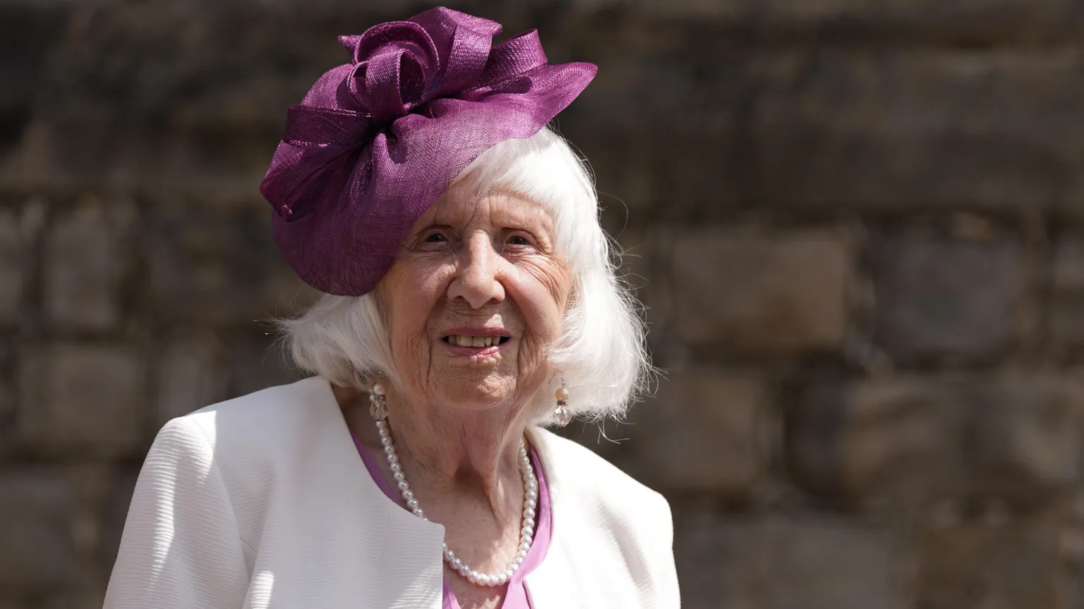 Betty Brown is staring into the camera and smiling. She has a purple flower headband on her head.