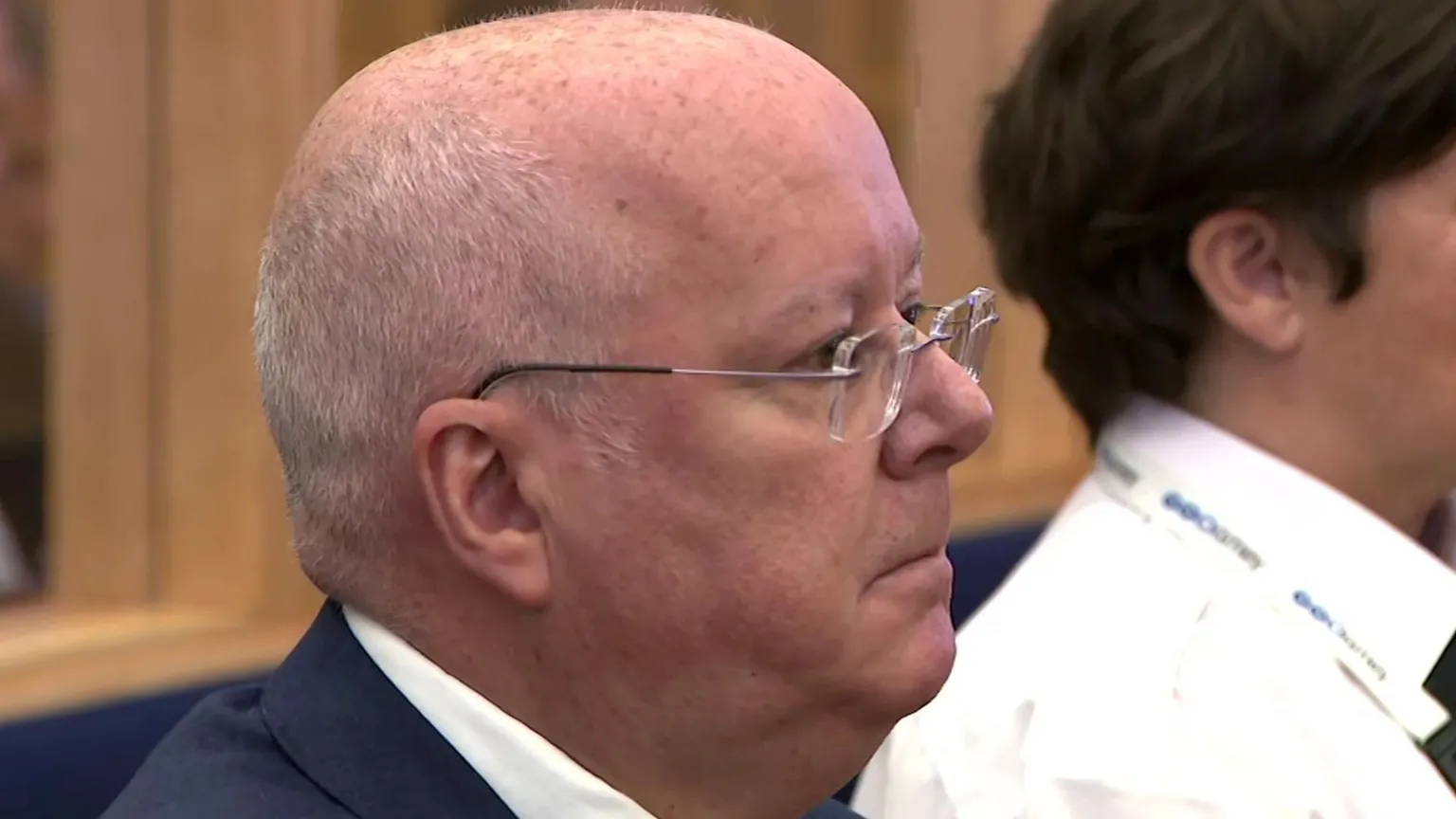 Peter Murrell sitting in court next to a prison guard