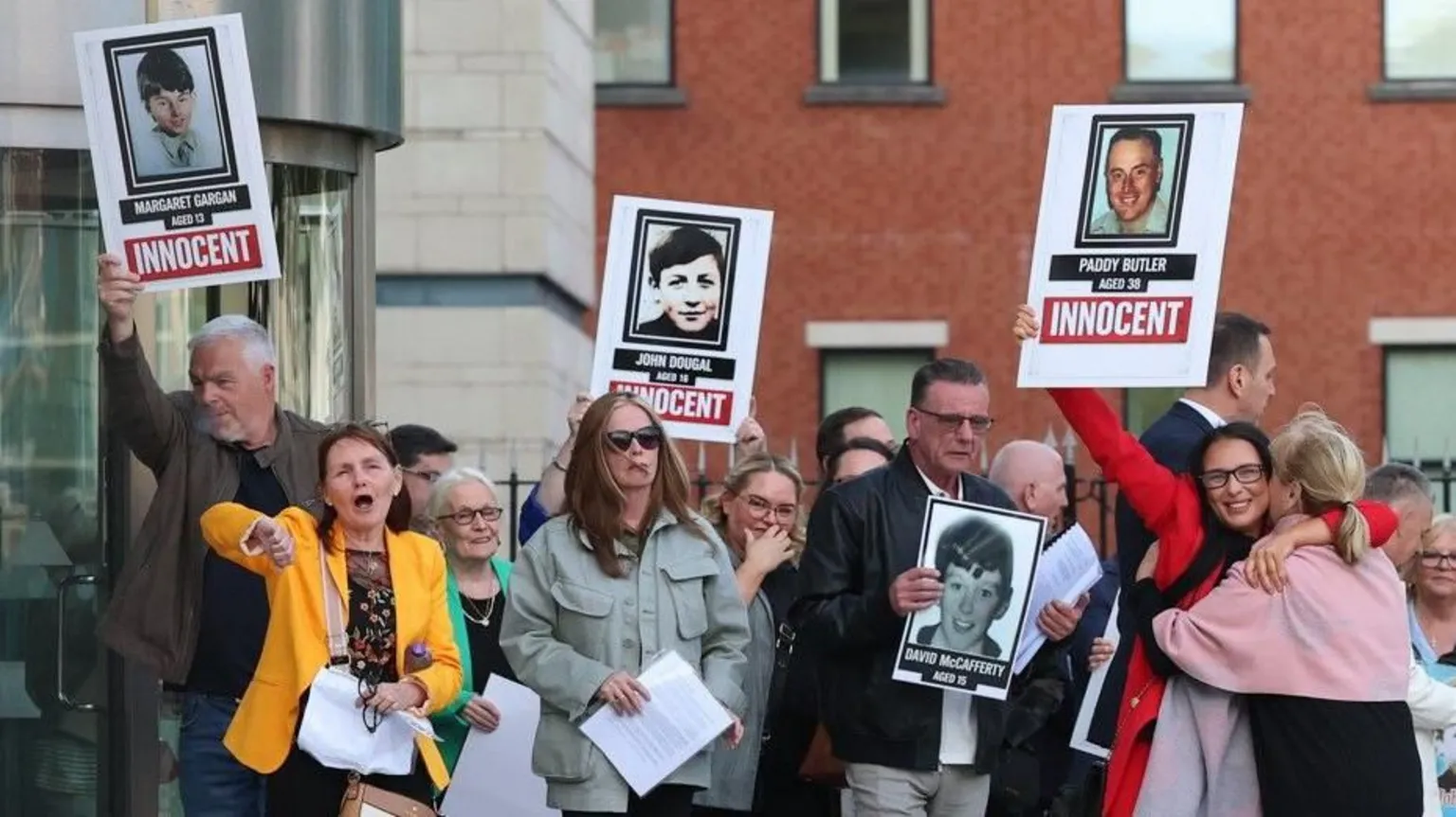  Various people hold up placards relating to the Springhill estate shootings in Belfast in 1972, on 30 April 2026